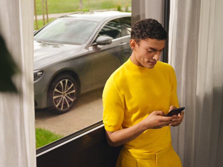 Person använder sin smartphone inomhus framför sin Mercedes-Benz