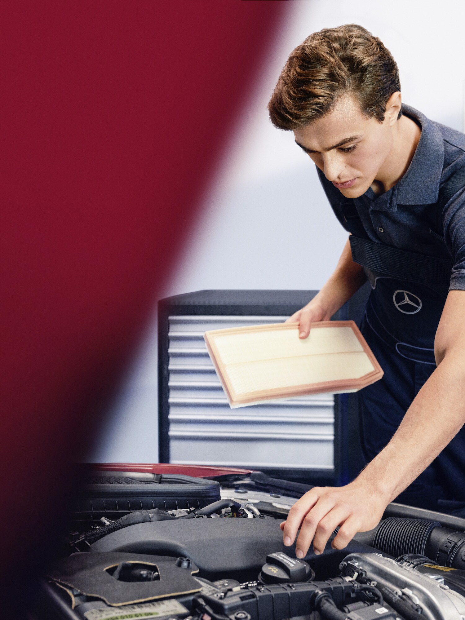 En Mercedes-Benz-tekniker kontrollerar ett luftfilter i motorrummet. 