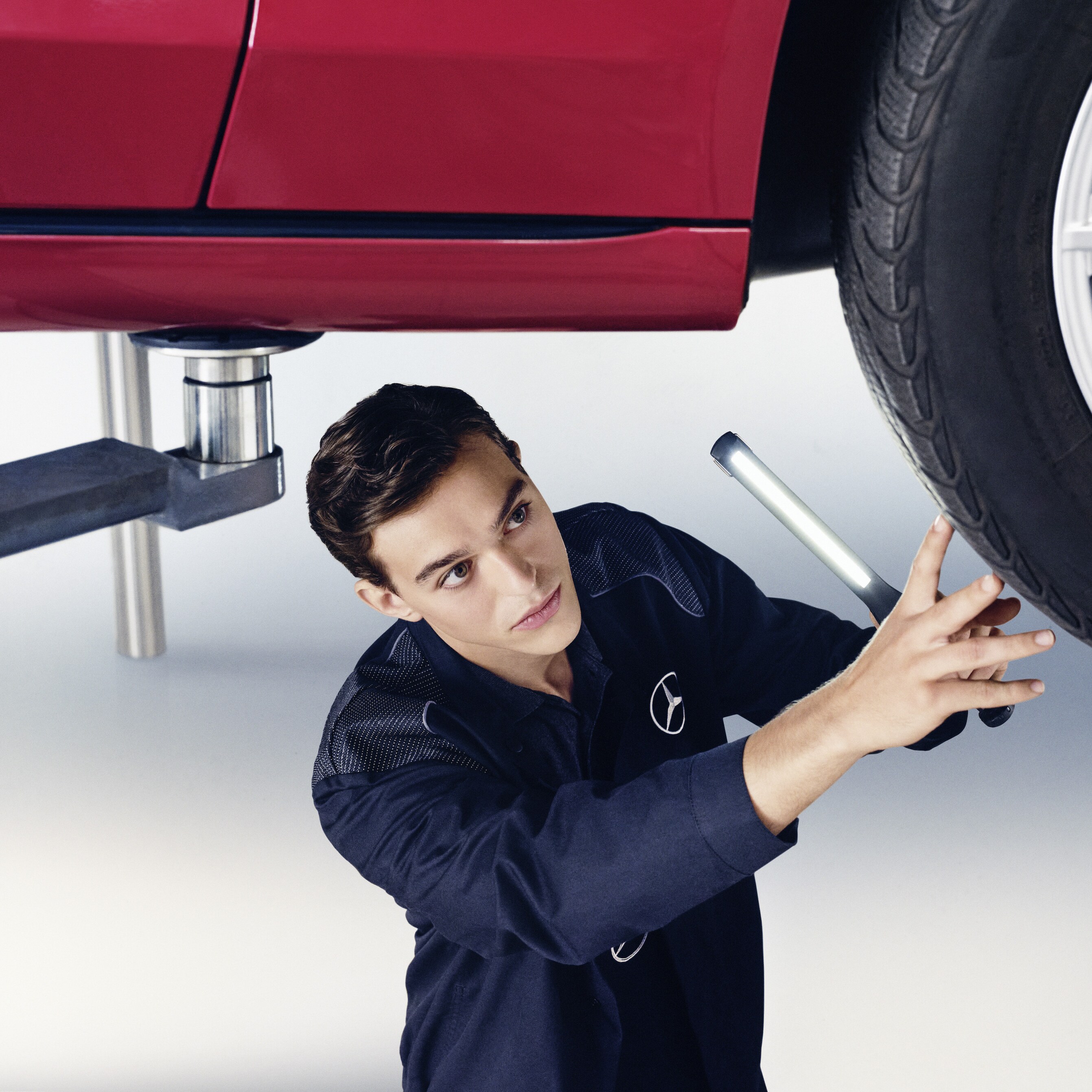 En Mercedes-Benz-tekniker kontrollerar undersidan på en bil.