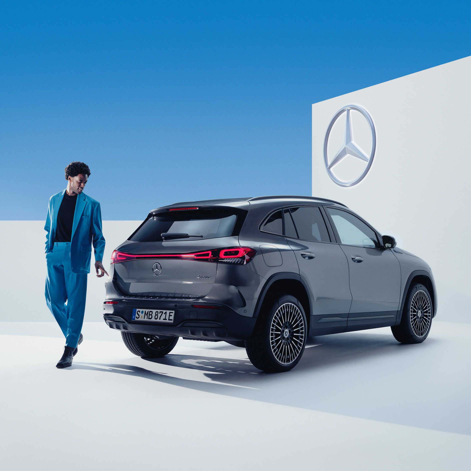 SmallRepair | Mercedes-Benz En person i kostym står framför en grå Mercedes-Benz EQA.