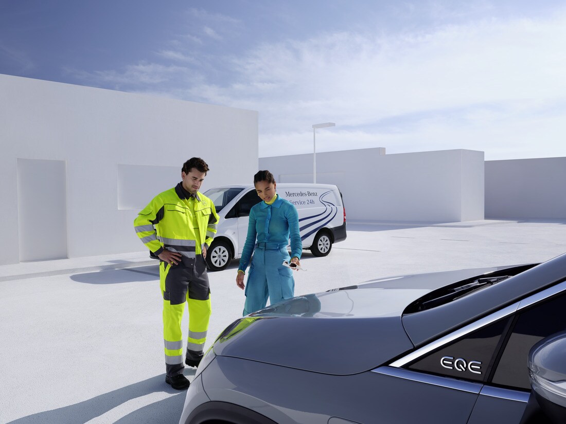 Man får hjälp av Mercedes-Benz mekaniker framför en blå Mercedes-Benz SUV