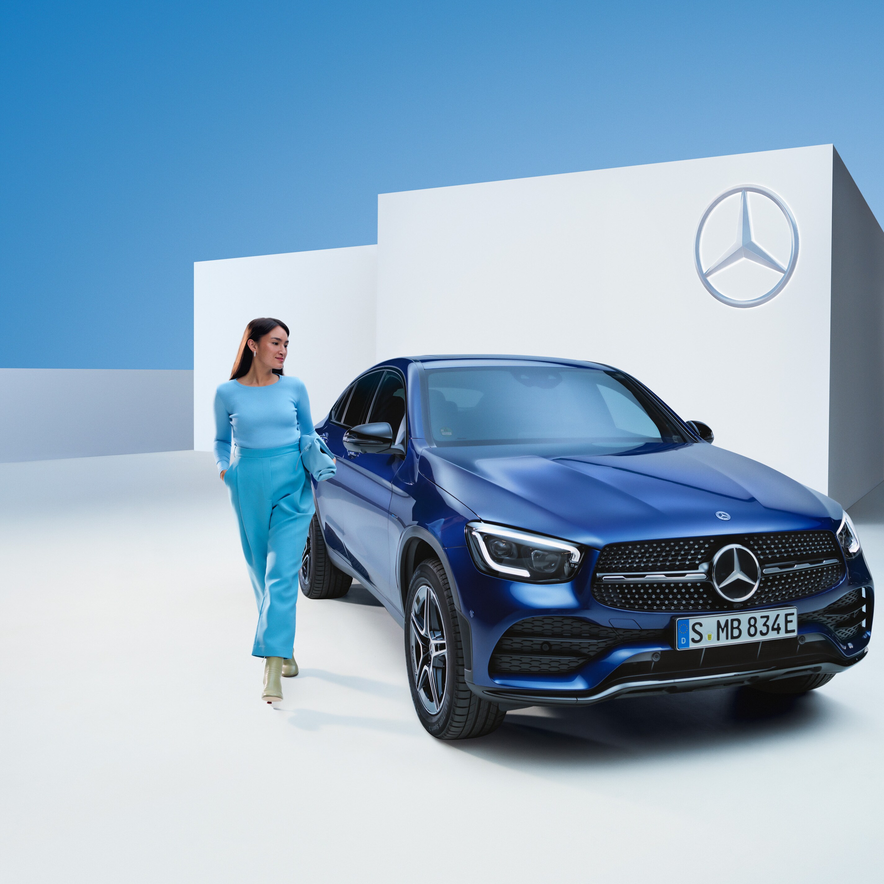 Kvinna står bredvid sin blåa Mercedes-Benz Coupé