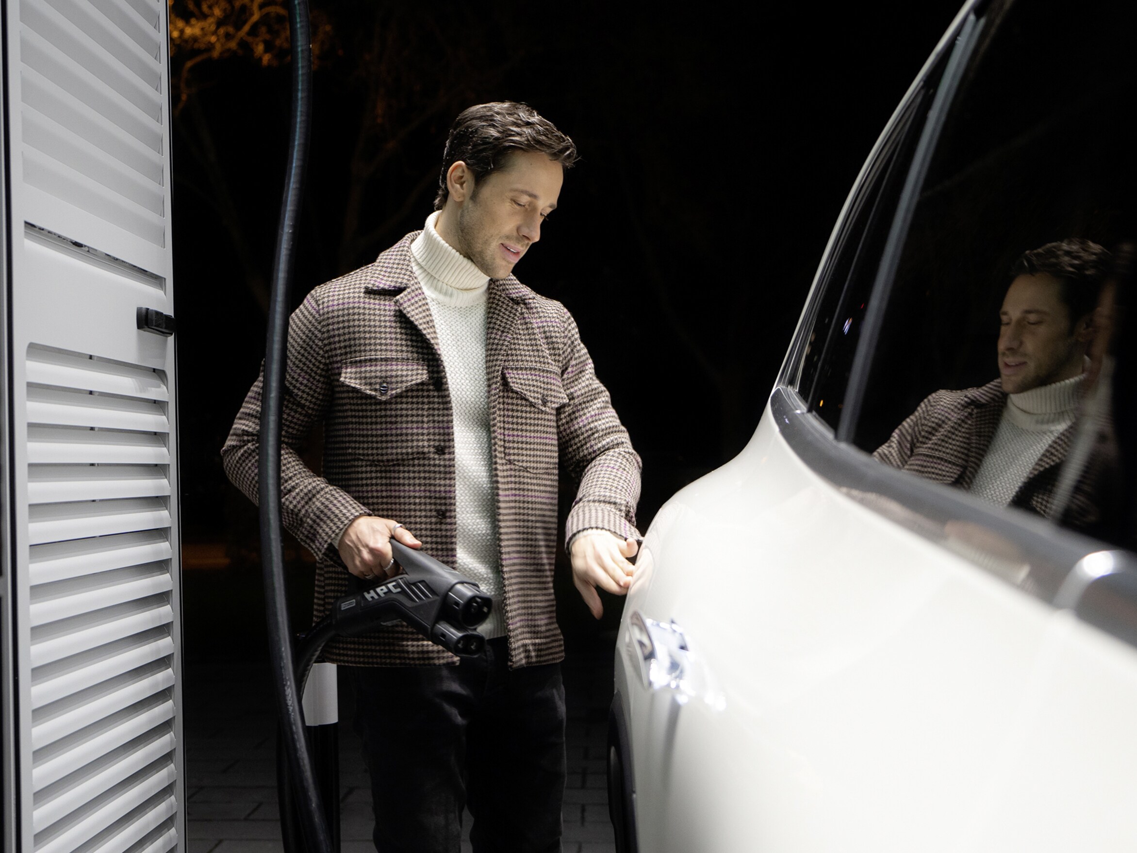 En man laddar sin Mercedes-Benz elbil vid laddstation.