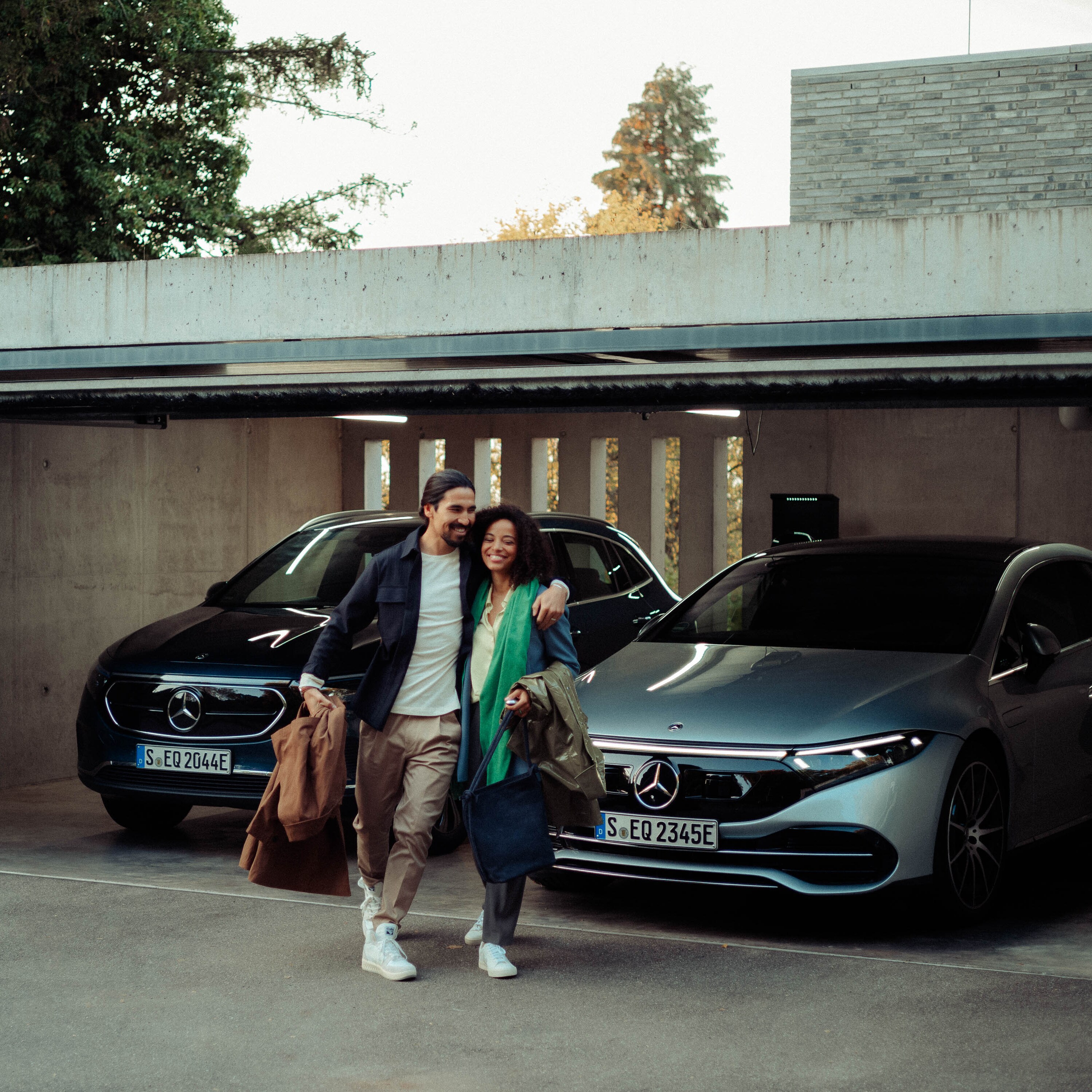 Kvinna och man lämnar garage med parkerade EQS Sedan och EQA