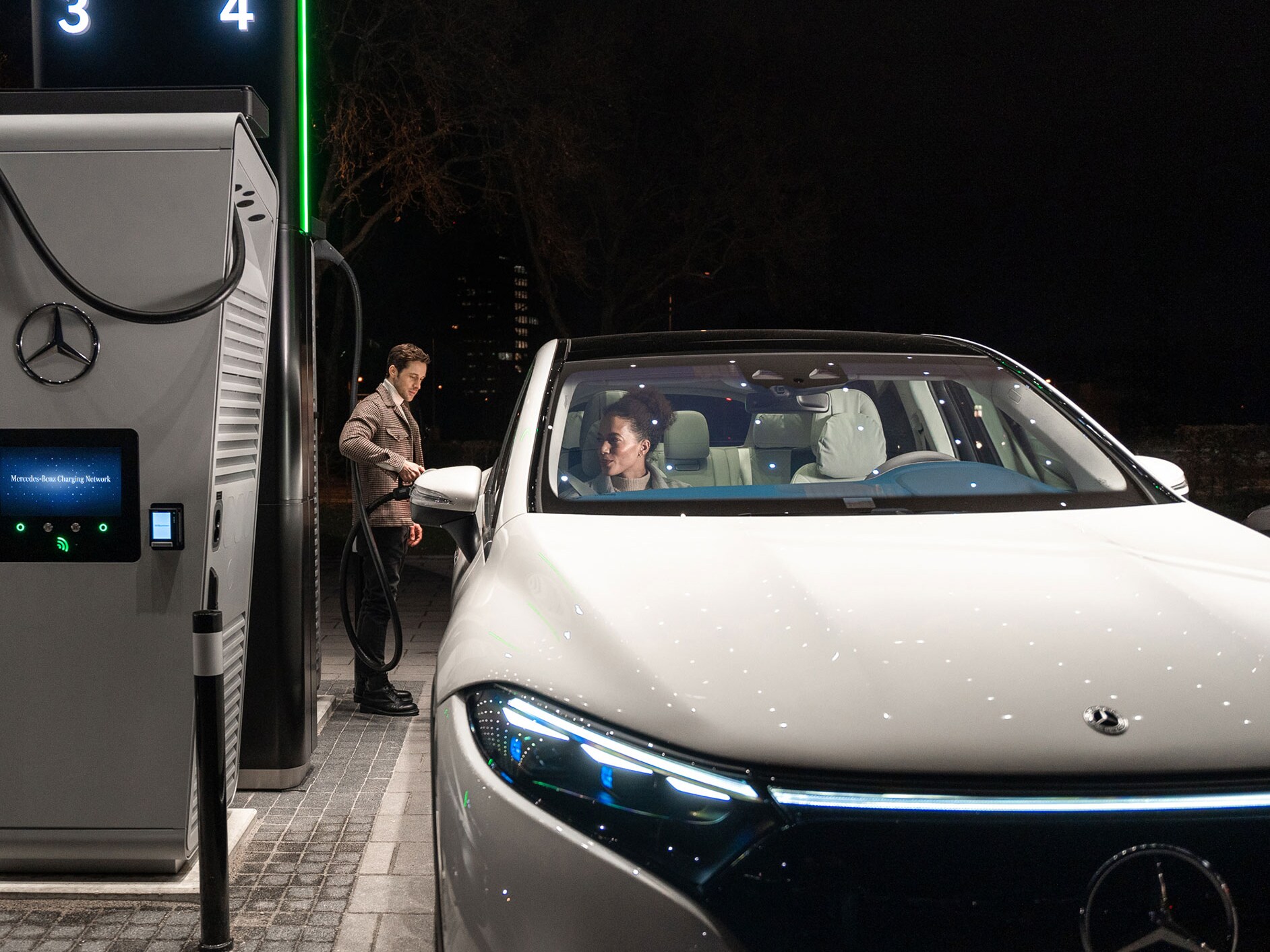 Mercedes-Benz CLA står på en gata och är ansluten till en laddningsstation.