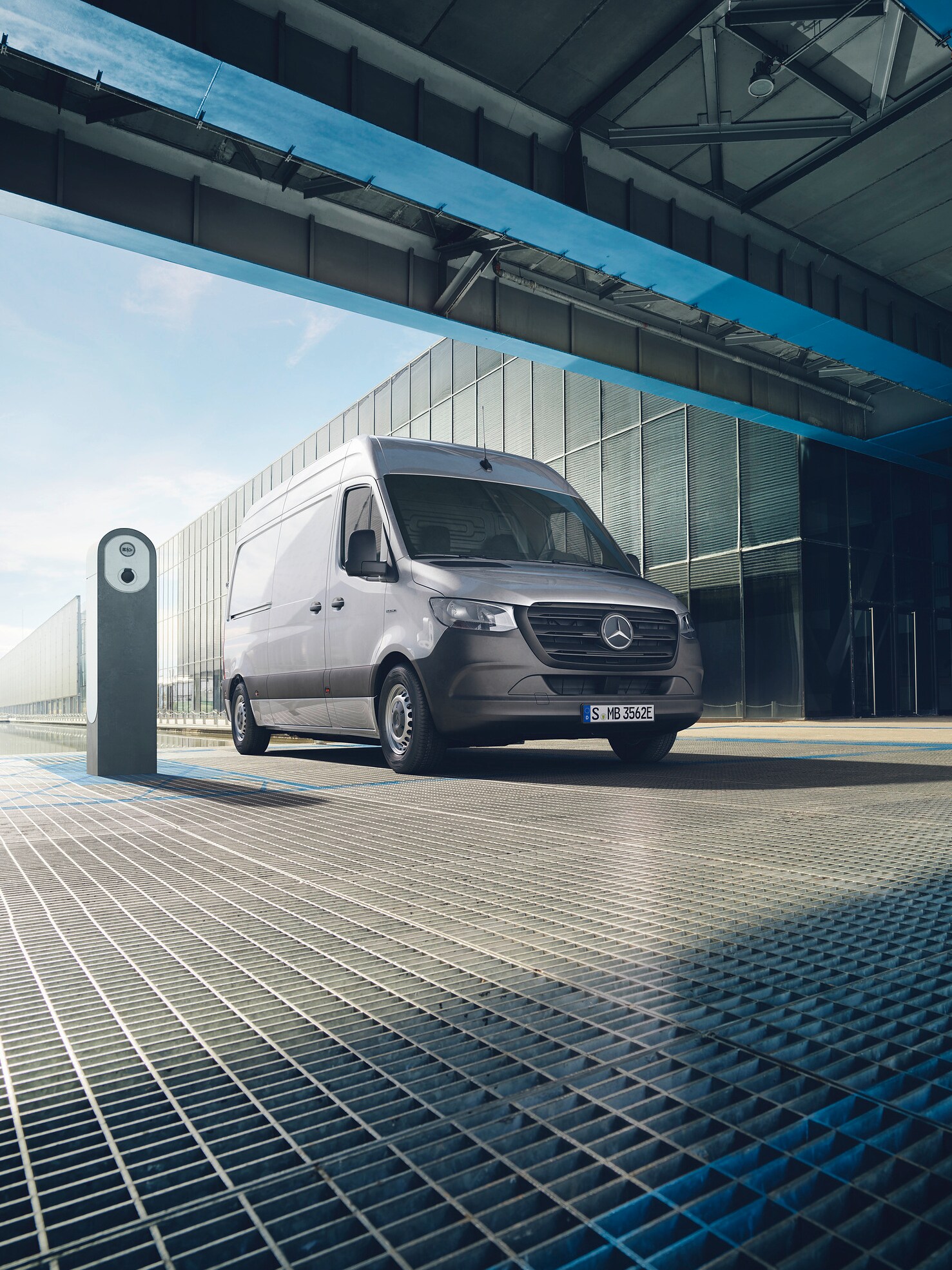 En silvrig Mercedes-Benz eSprinter parkerad vid laddstolpe