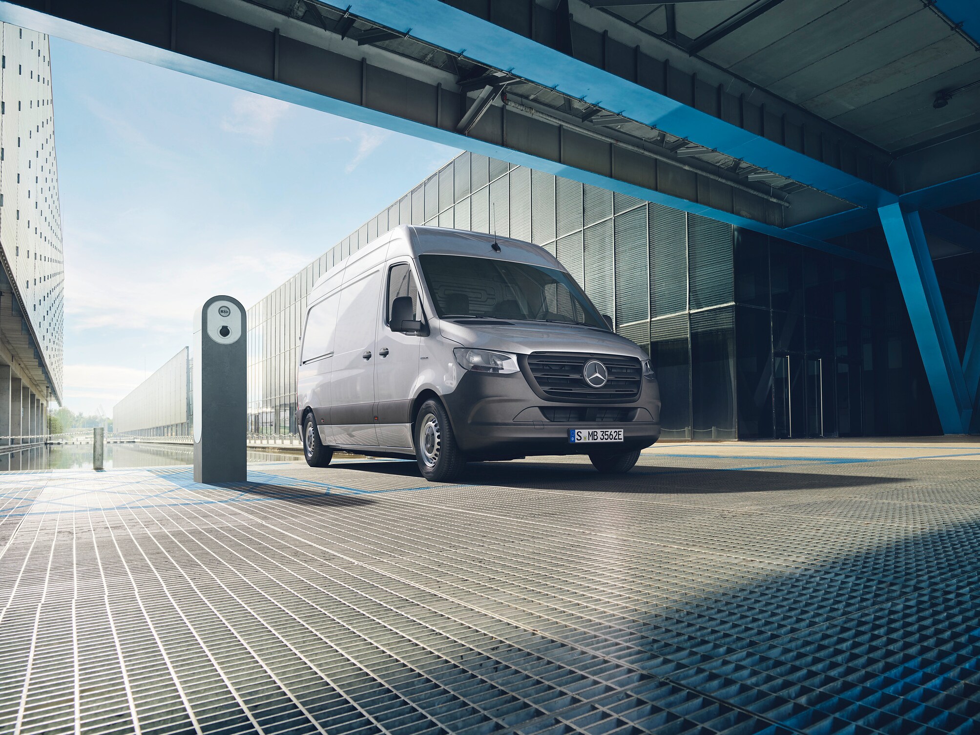 En silvrig Mercedes-Benz eSprinter parkerad vid laddstolpe