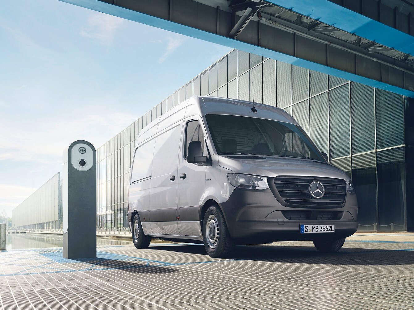 En silvrig Mercedes-Benz eSprinter parkerad vid laddstolpe.