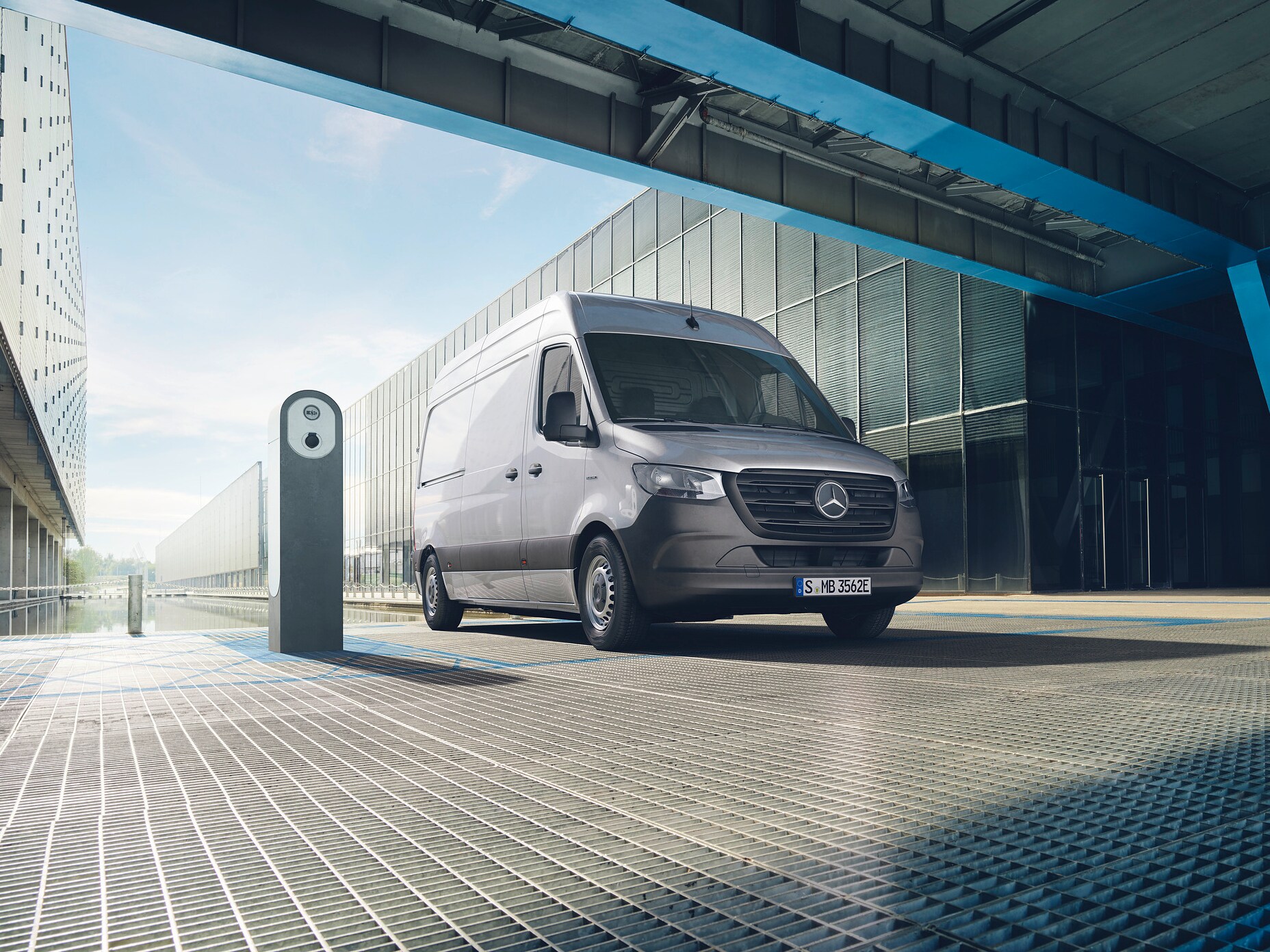 En silvrig Mercedes-Benz eSprinter parkerad vid laddstolpe