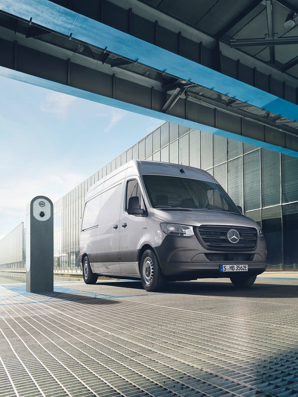 En silvrig Mercedes-Benz eSprinter parkerad vid laddstolpe