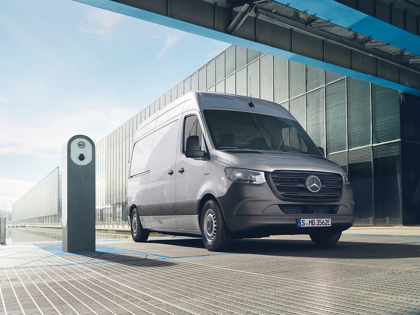 En silvrig Mercedes-Benz eSprinter parkerad vid laddstolpe