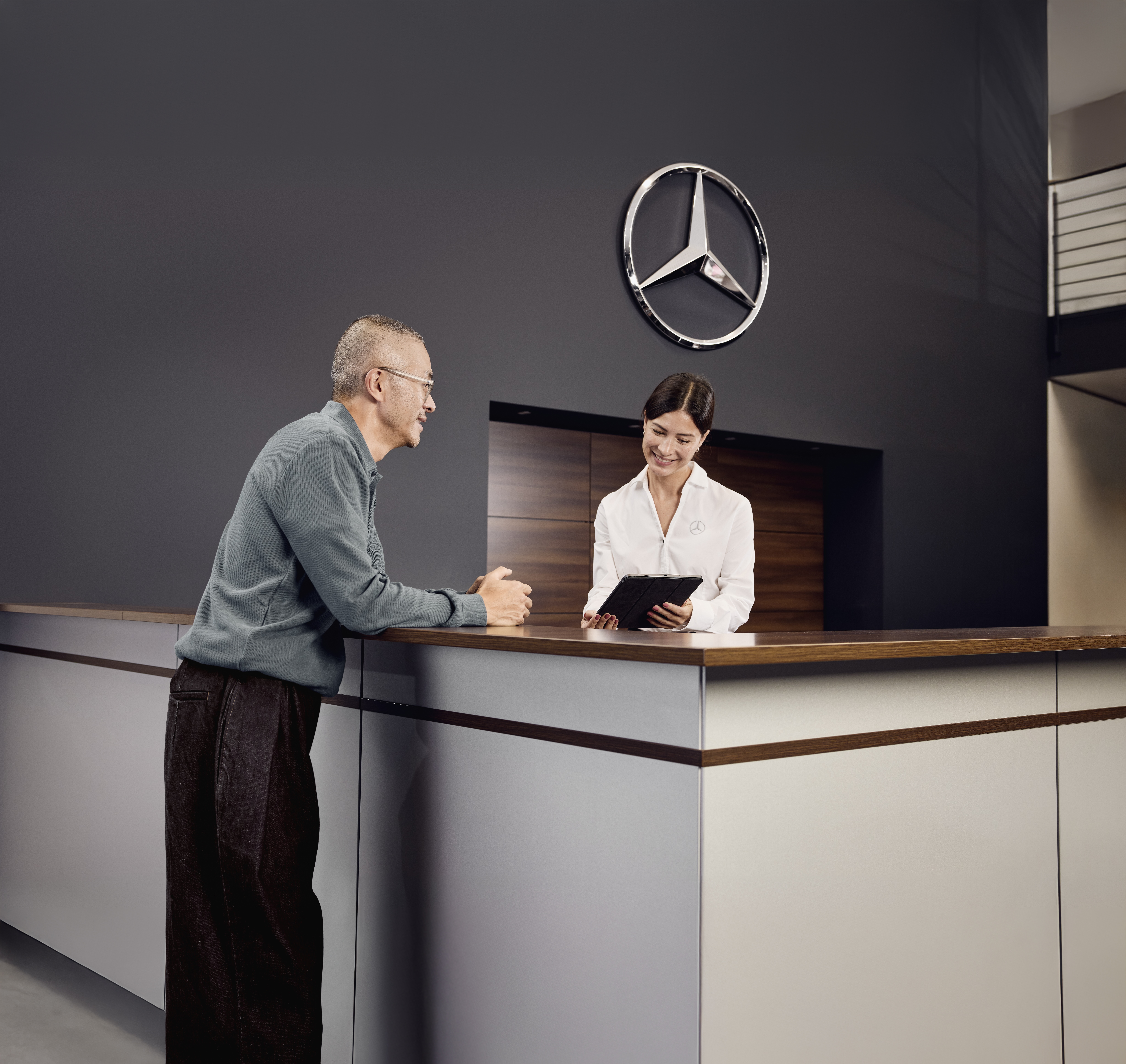 Leasa en 7-sitsig elbil | 7-sitsiga elbilar för familjen | Mercedes-Benz Mercedes-Benz-säljare pratar med kund i receptionen.