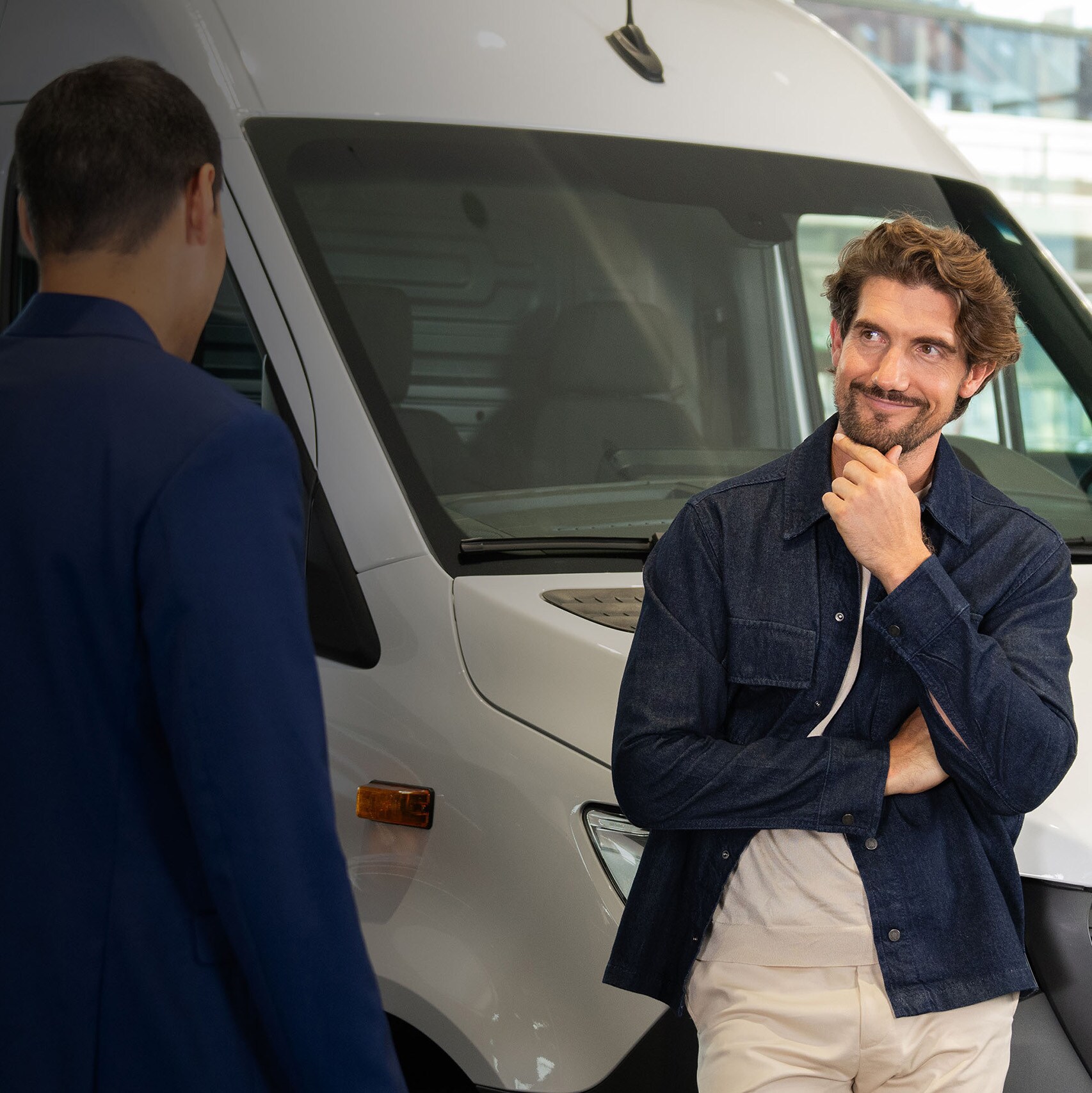 Man lutar sig mot en transportbil och pratar med en annan man.