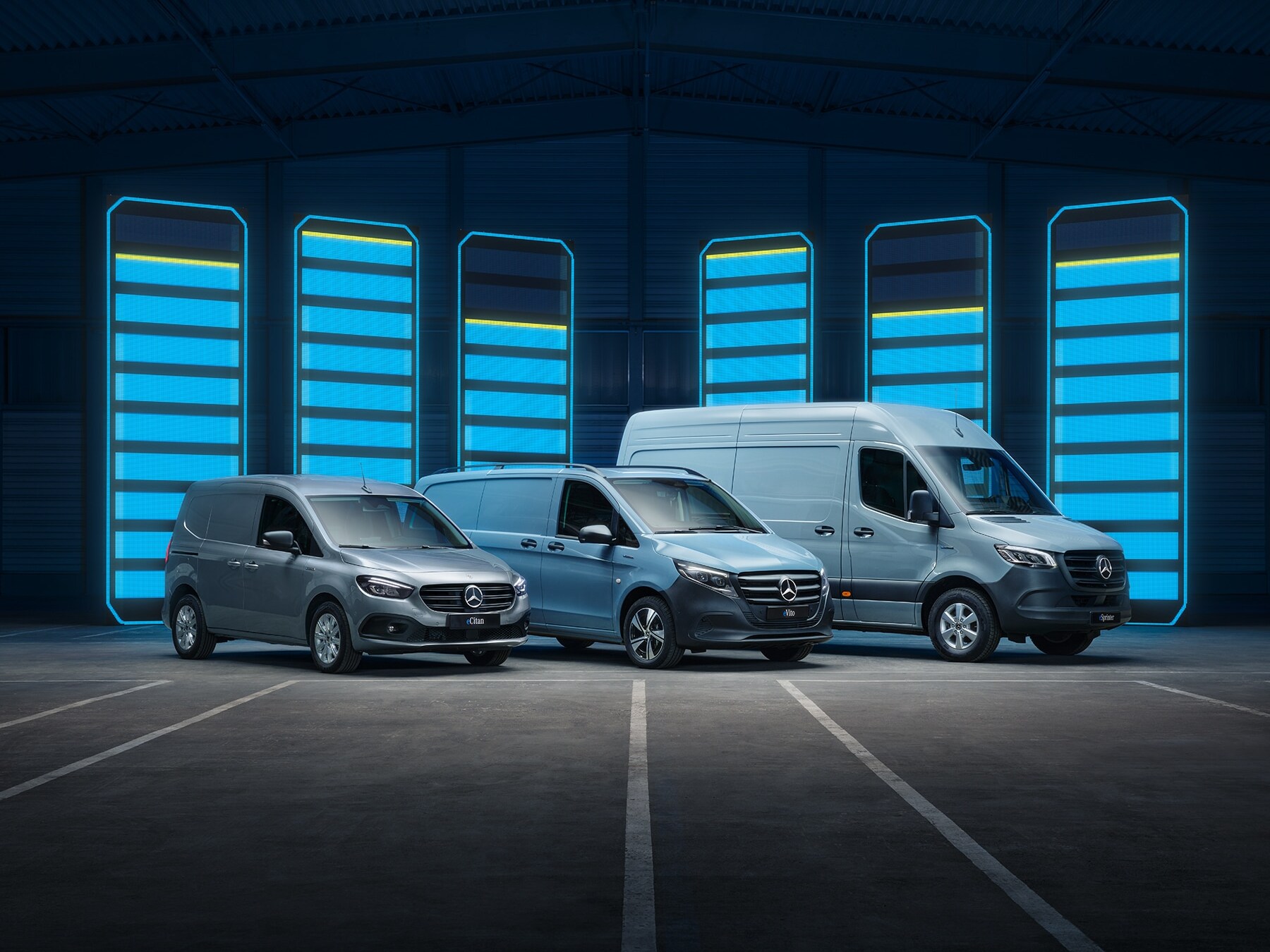Mercedes‑Benz utbud av eldrivna transportbilar visas i ett futuristiskt lager med upplysta laddningsstaplar.