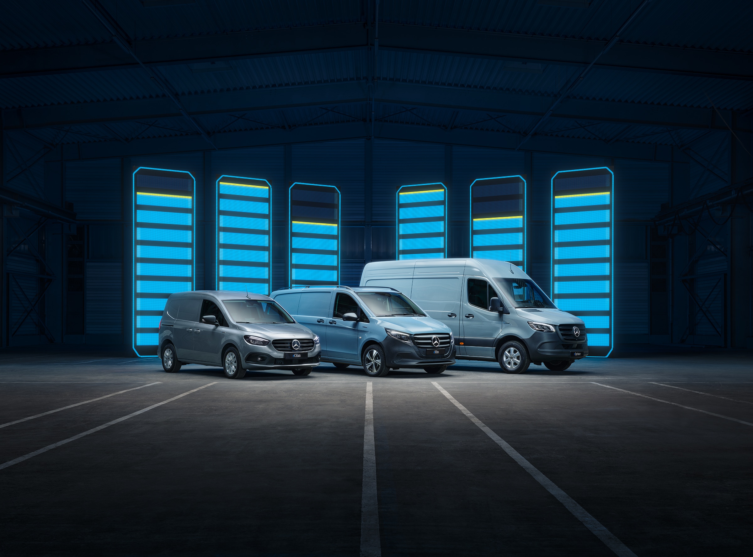 Mercedes‑Benz utbud av eldrivna transportbilsmodeller | Transportbilshistoria | Mercedes-Benz Mercedes‑Benz utbud av eldrivna transportbilar visas i ett futuristiskt lager med upplysta laddningsstaplar.