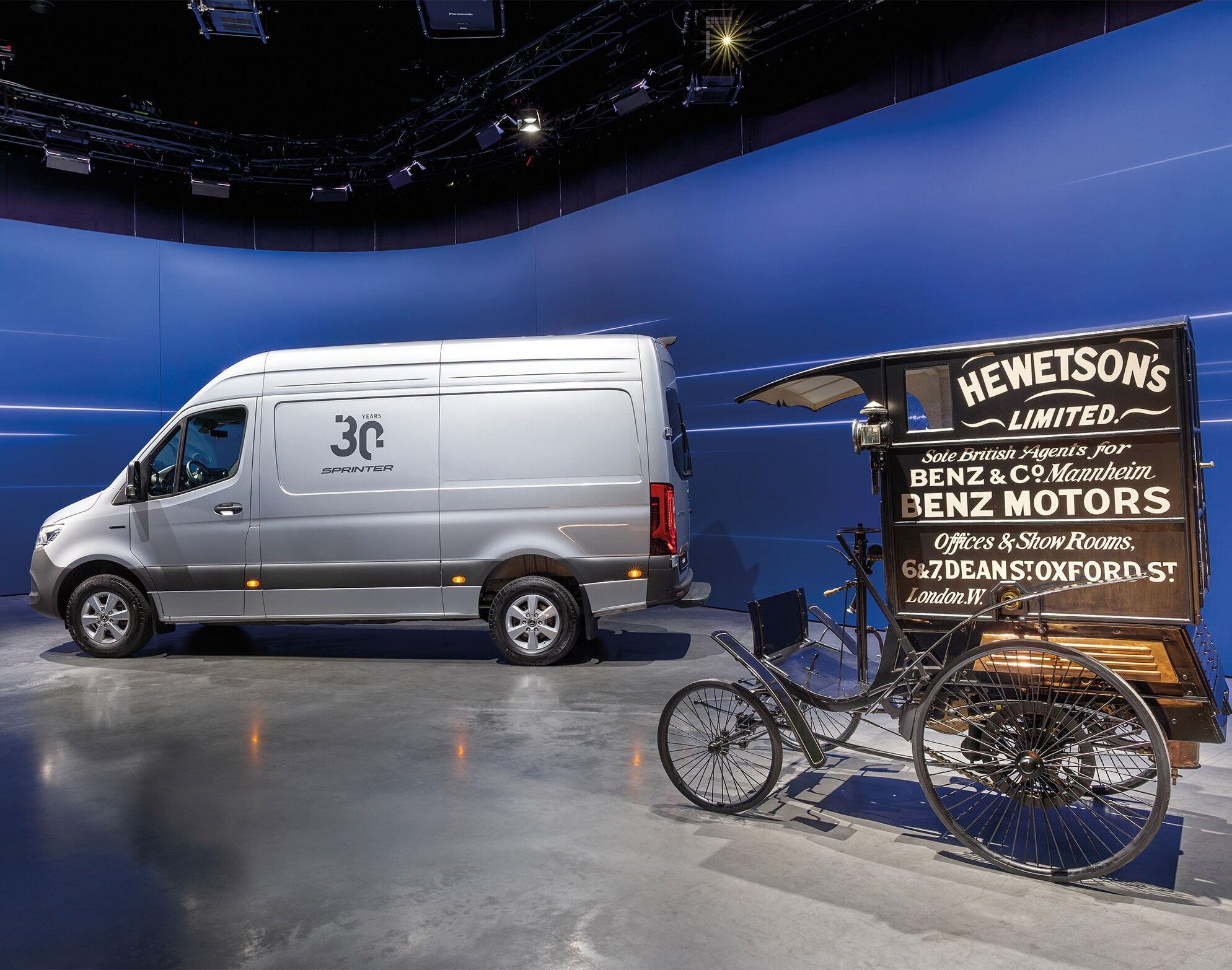 Transportbilen Mercedes-Benz Sprinter och den historiska transportbilen Benz visas i en modern bilhall