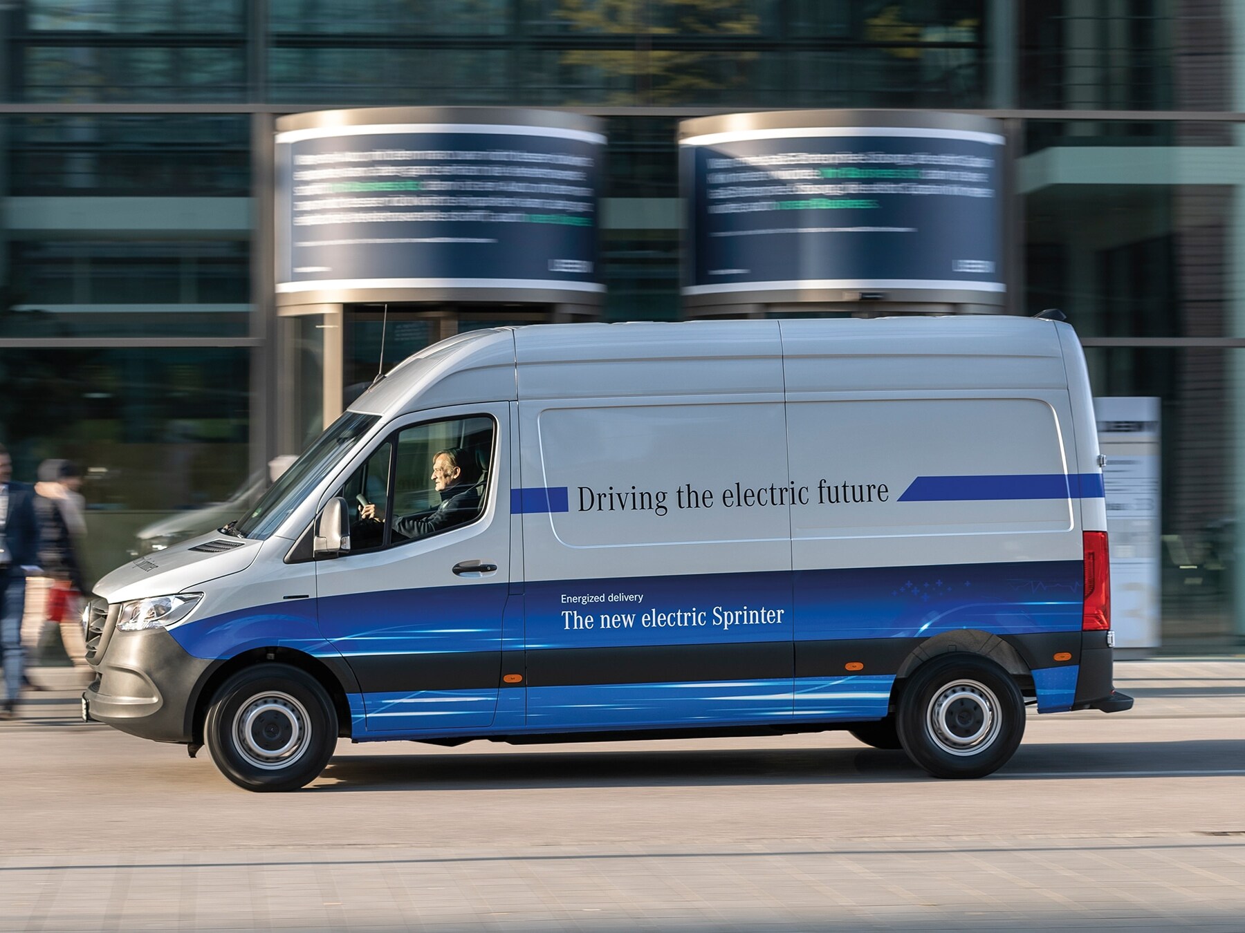 Skåpbilen Mercedes‑Benz eSprinter kör på en modern stadsgata
