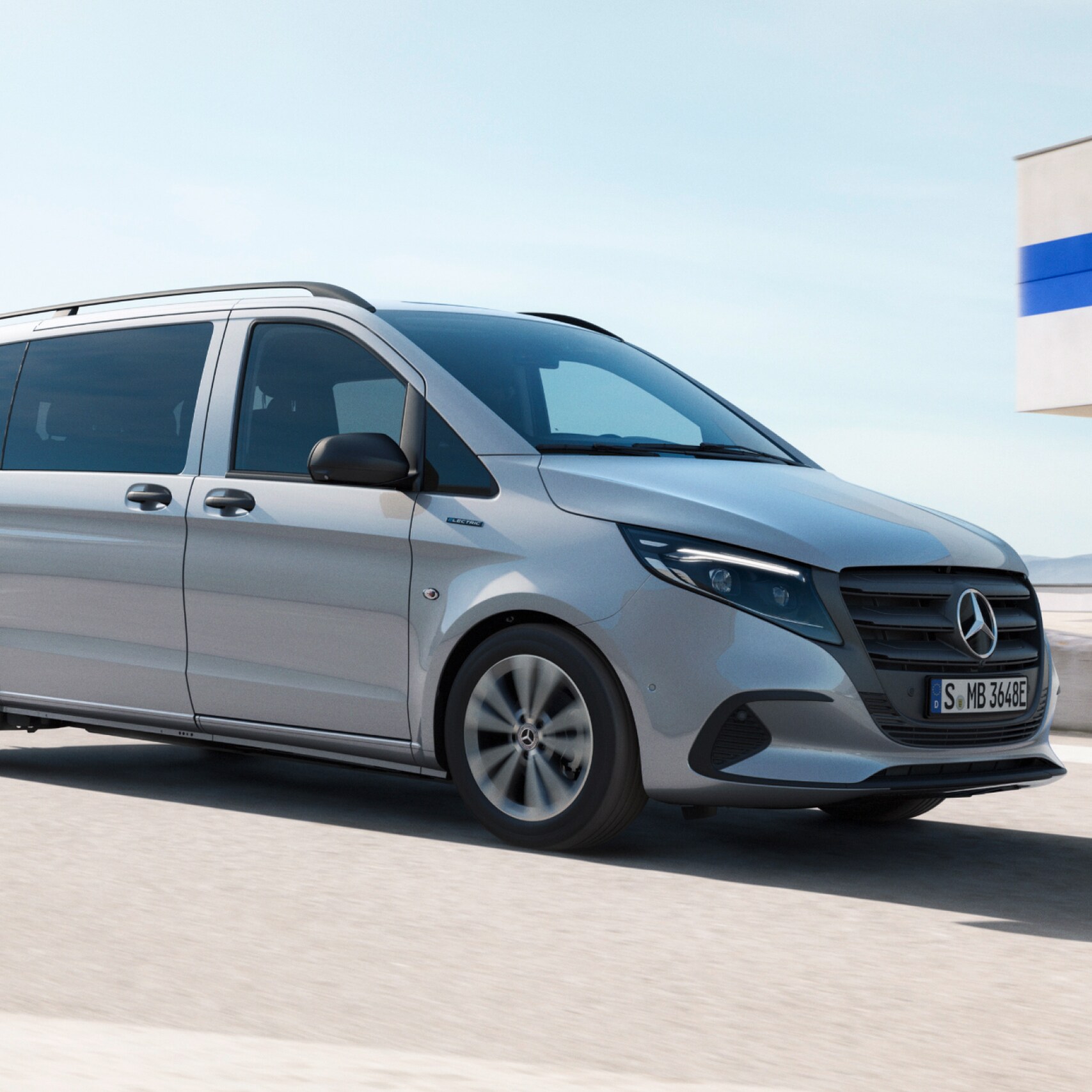 Silverfärgad Mercedes-Benz transportbil kör på parkeringsplats ovanpå en byggnad