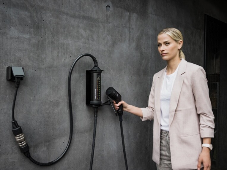 Kvinna håller laddkabel från Mercedes-Benz