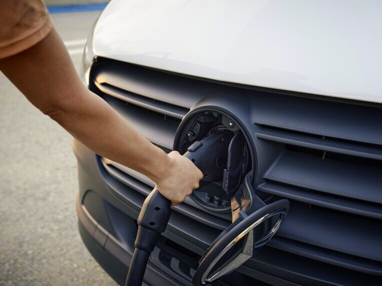 Laddning | Mercedes-Benz Transportbilar Man ansluter laddkabel till elektrisk Mercedes-Benz transportbil