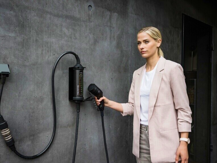Kvinna håller i Mercedes-Benz laddkabel