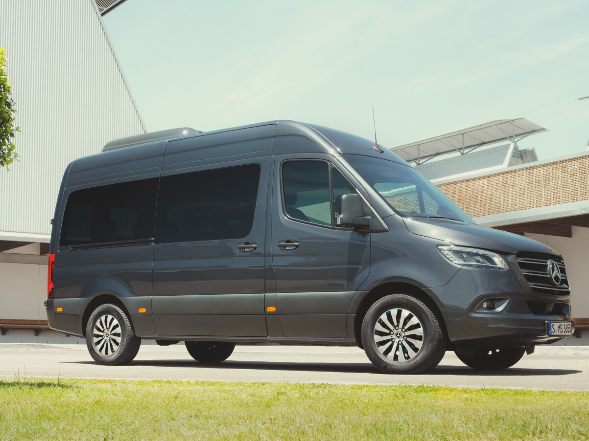 En Mercedes-Benz Sprinter Tourer står parkerad framför en byggnad