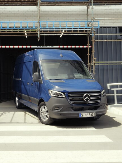 Blå Mercedes-Benz Sprinter skåpbil kör ut från byggarbetsplats