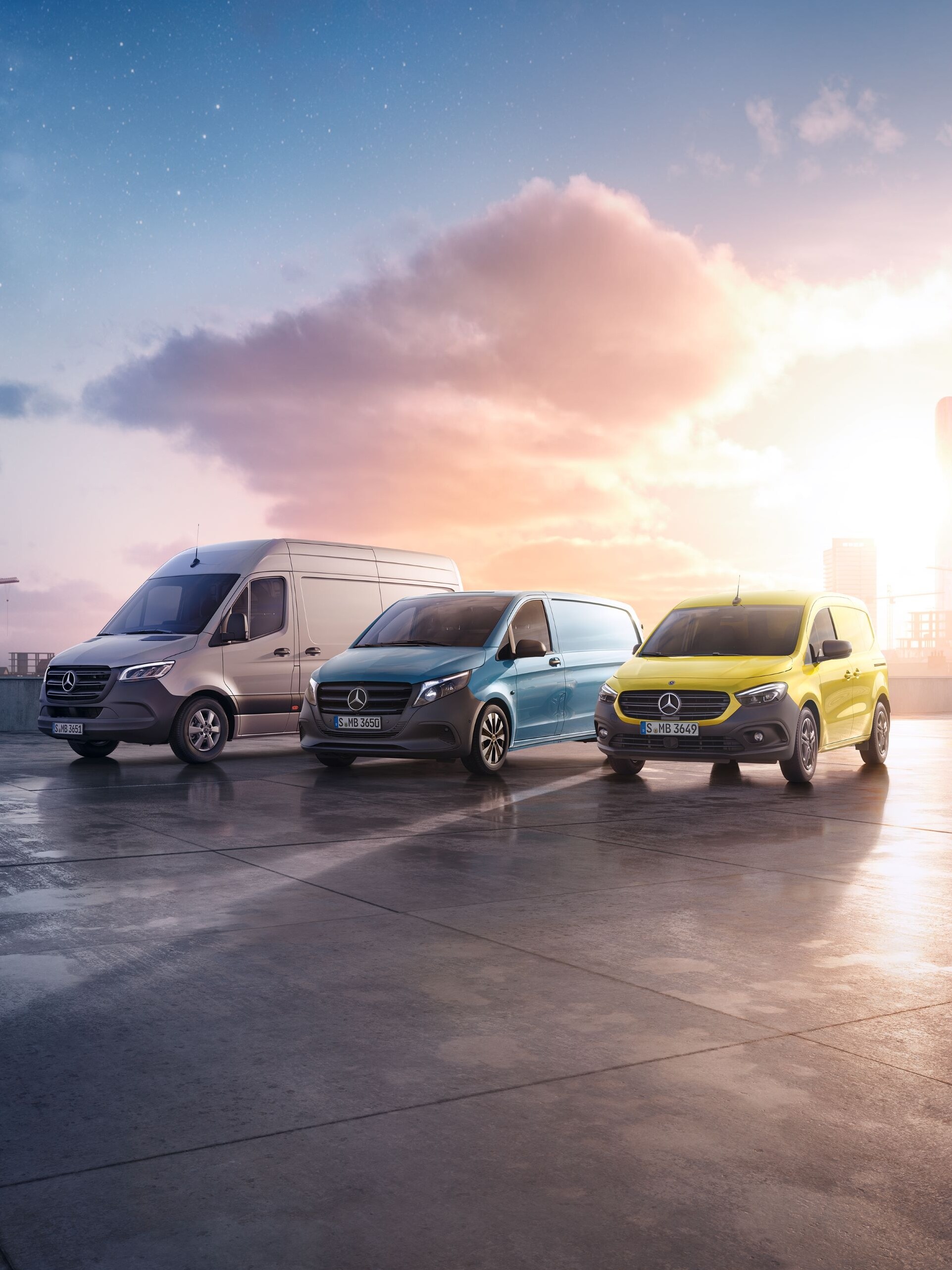 Tre Mercedes-Benz skåpbilar parkerade på tak med stadsvy i bakgrunden