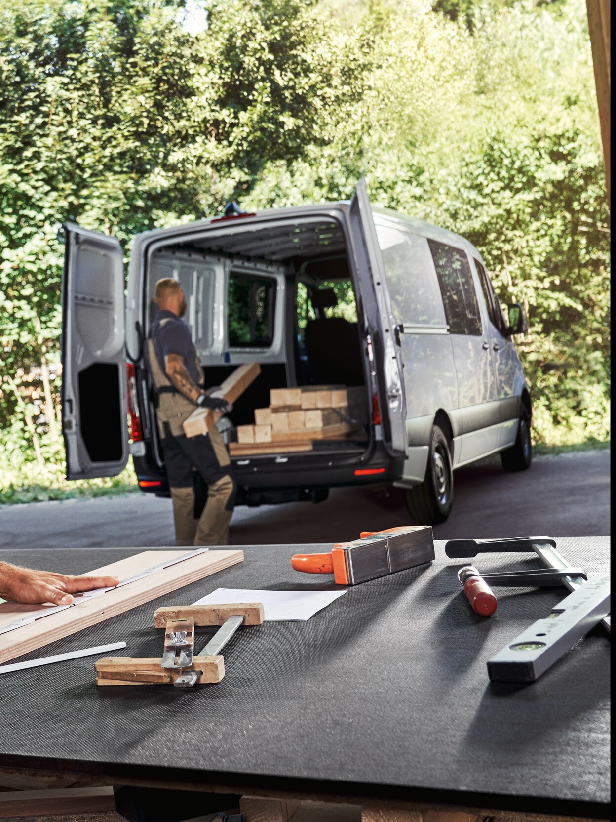 Två hantverkare arbetar, en lastar material i Mercedes-Benz transportbil