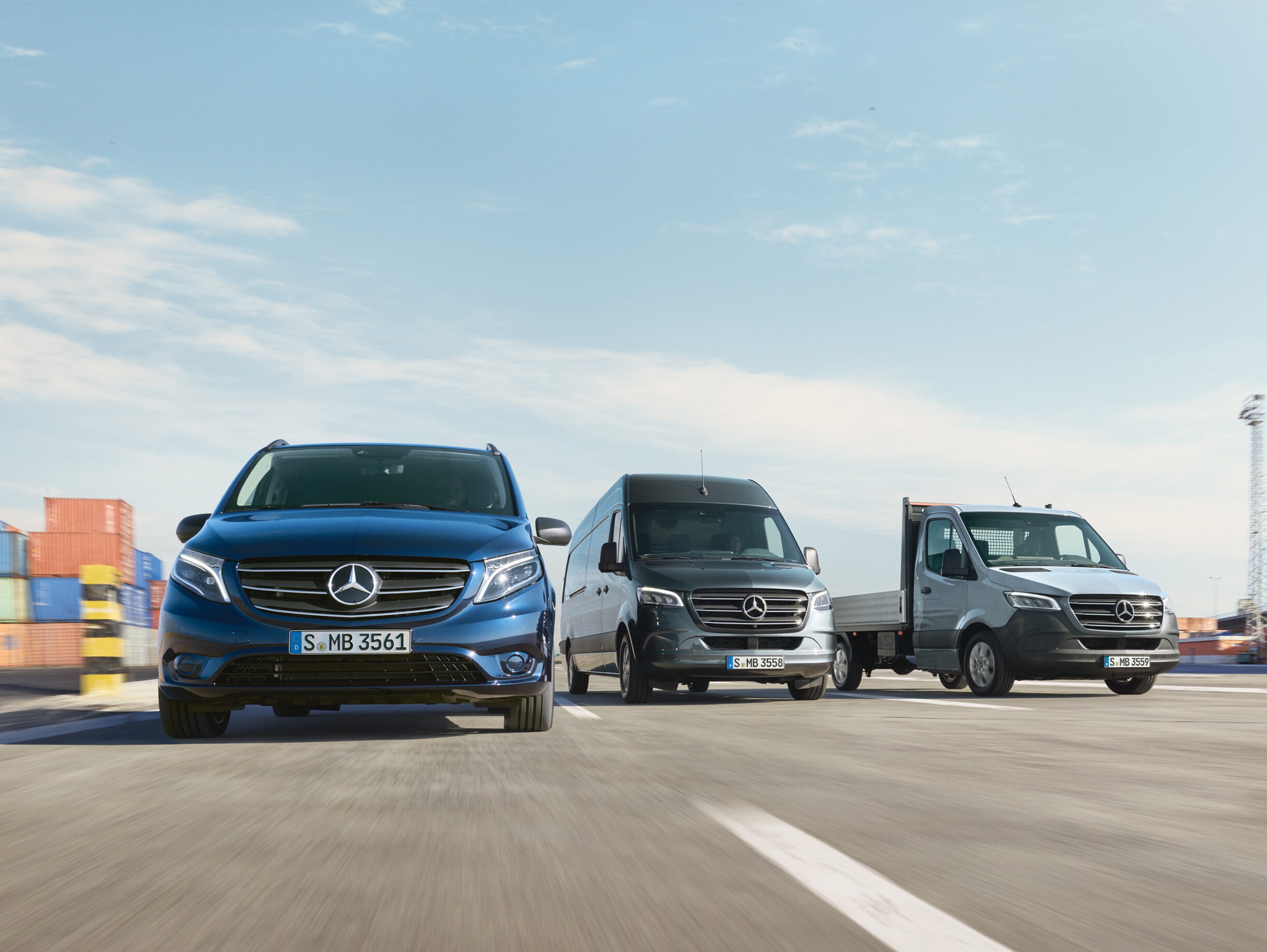 Ett antal Mercedes-Benz transportbilar sida vid sida på en väg intill en lastkaj.