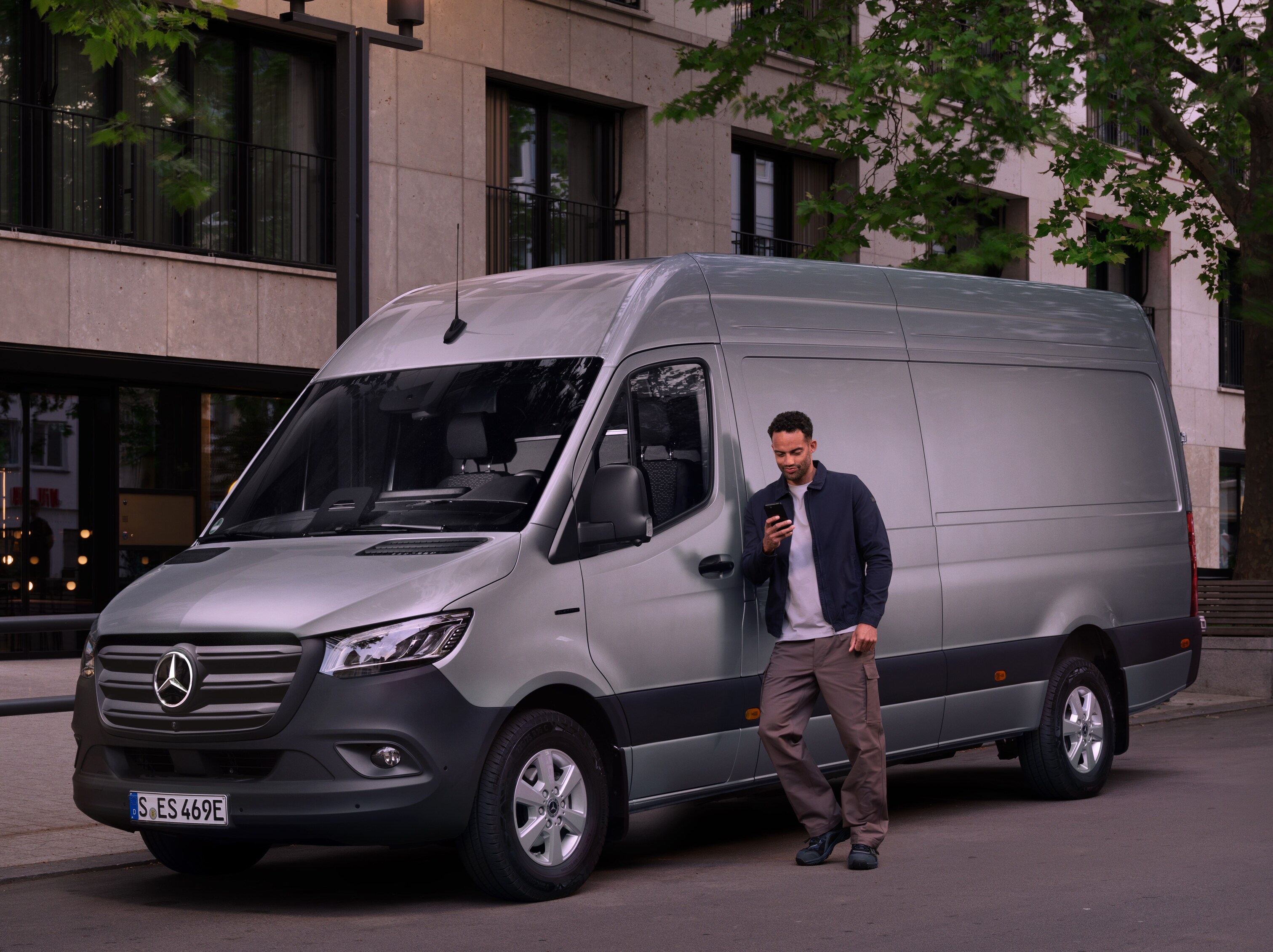 Man lutar sig mot en silverfärgad Mercedes-Benz Sprinter.