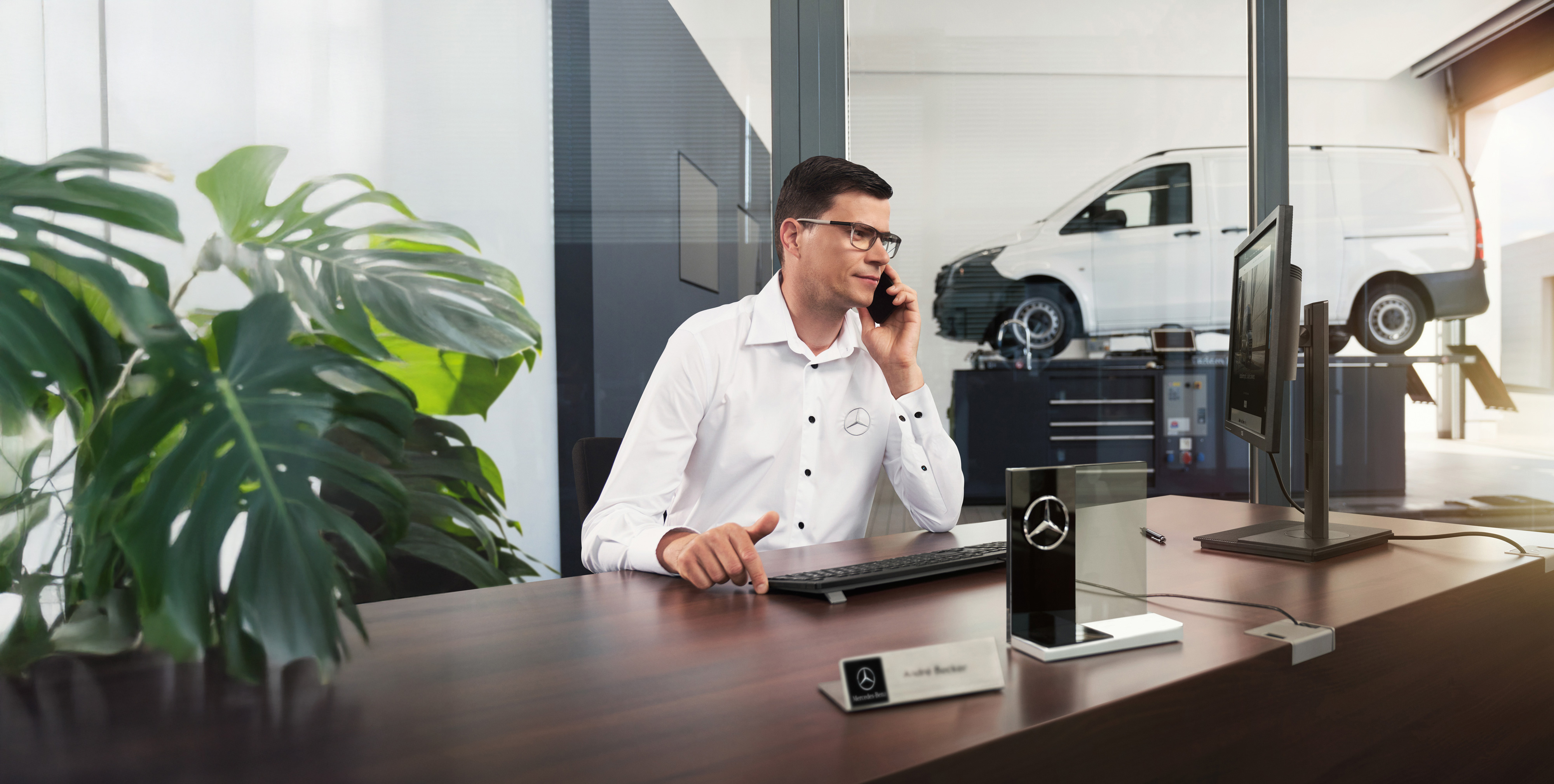 Mercedes-Benz | Vans Care En anställd på Mercedes-Benz pratar i telefon vid ett skrivbord.