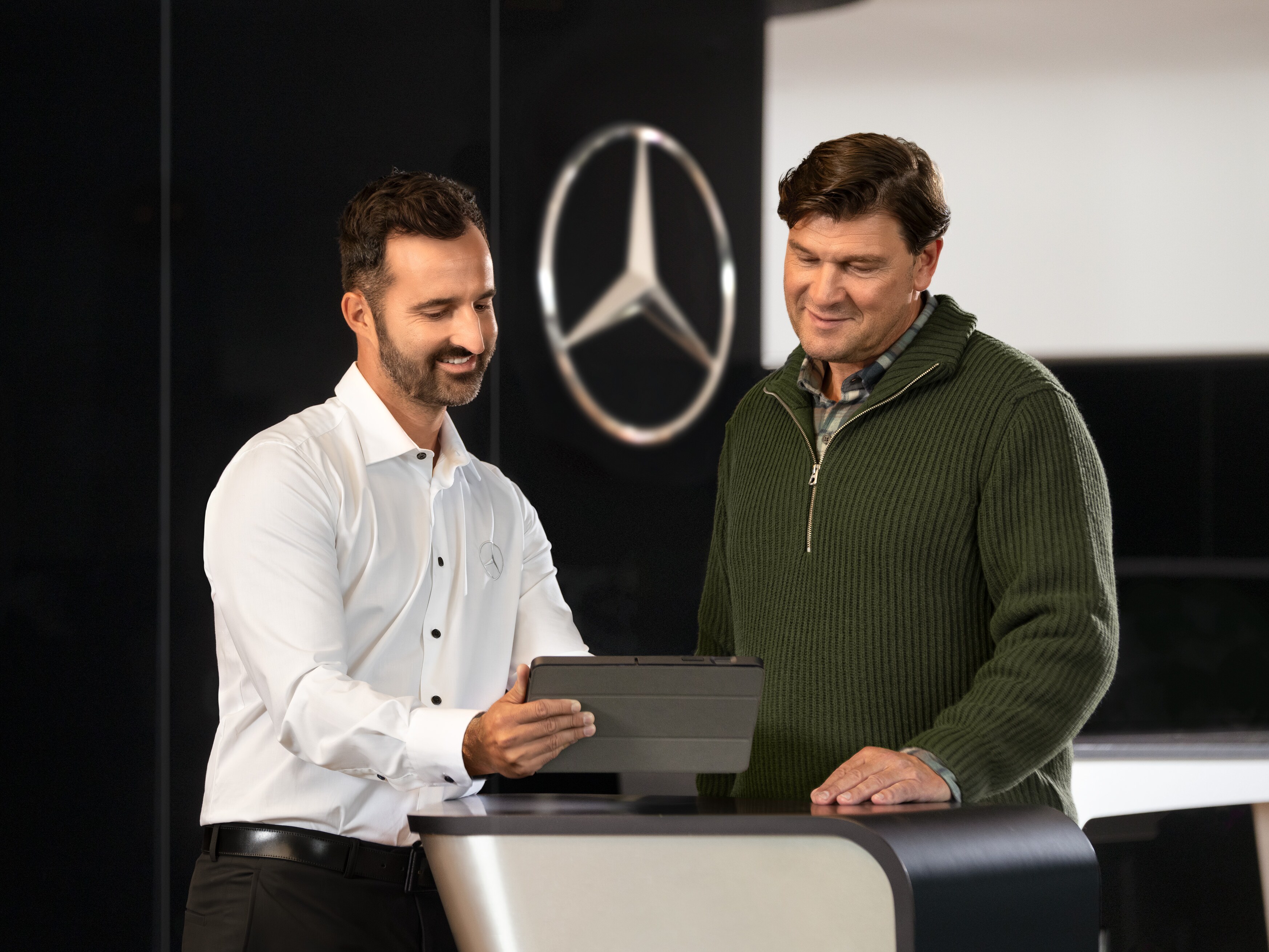 Mercedes-anställd ger råd till kunder vid disken med en surfplatta.