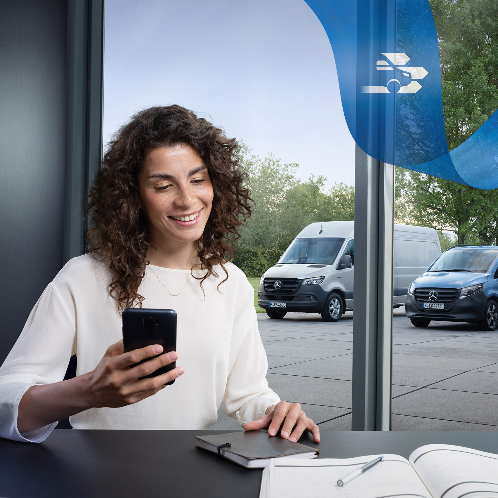 Mercedes-Benz | Kundtjänst Kvinna sitter vid ett skrivbord med smartphone.
