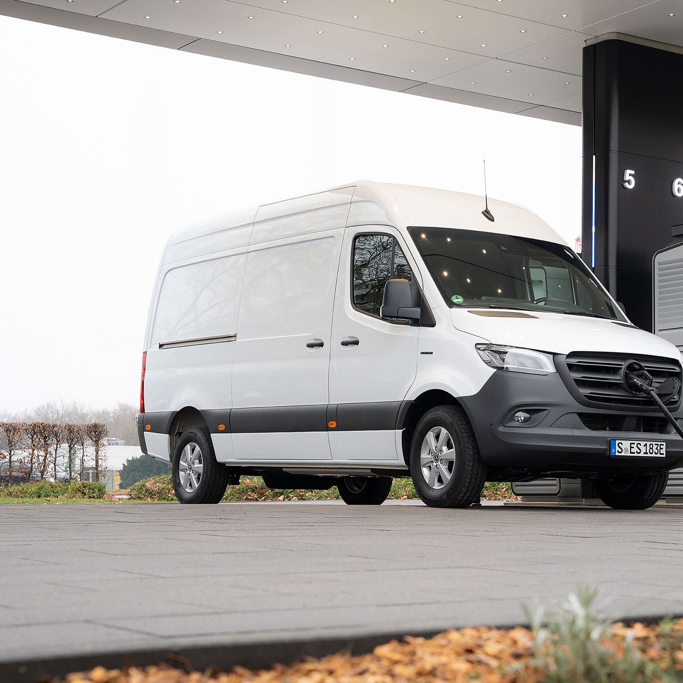 En transportbil från Mercedes-Benz framför en laddningsstation under laddning.