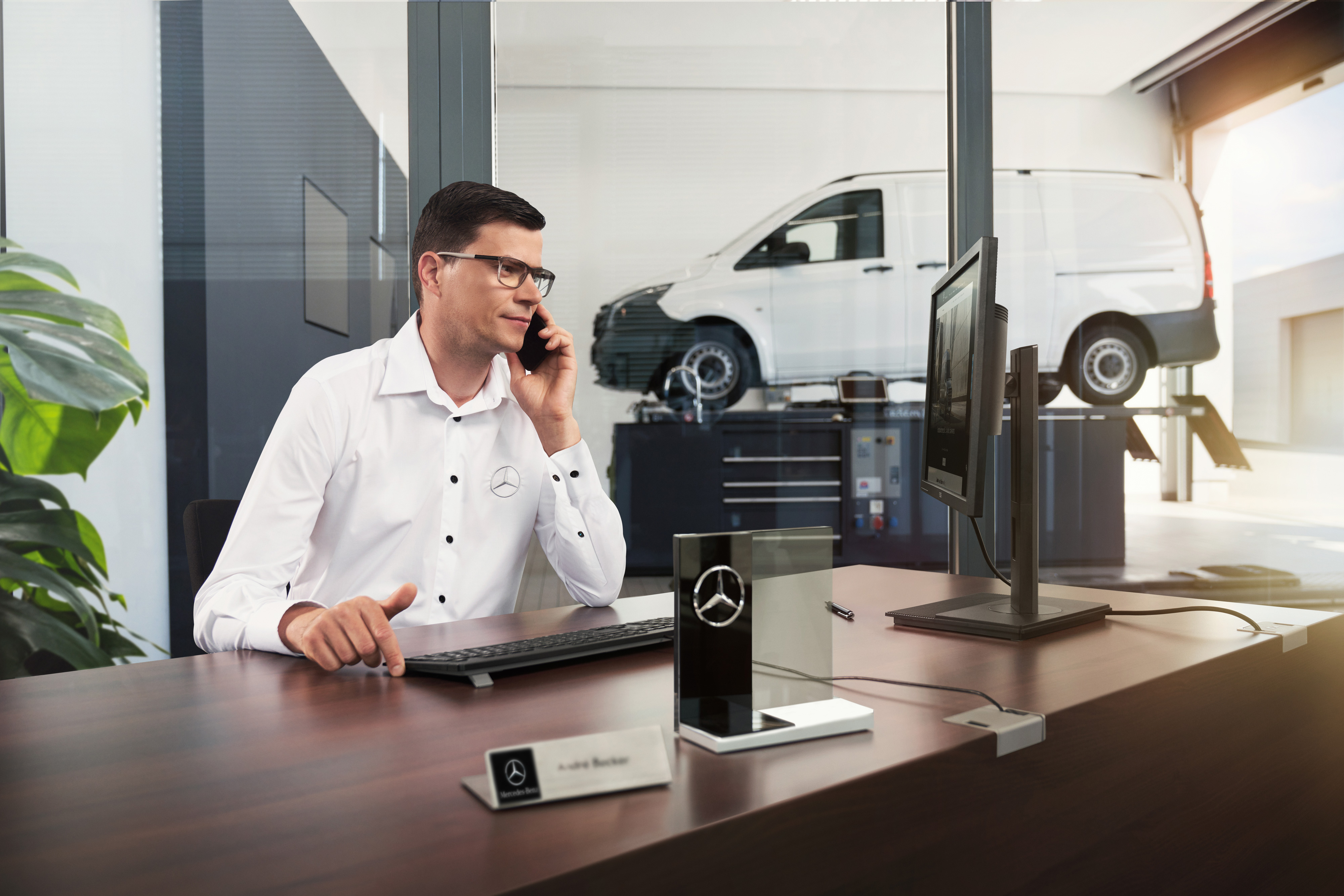 Mercedes-Benz | Bekvämlighet | Servicepartner Mercedes-Benz servicerådgivare talar i telefon på en verkstad.