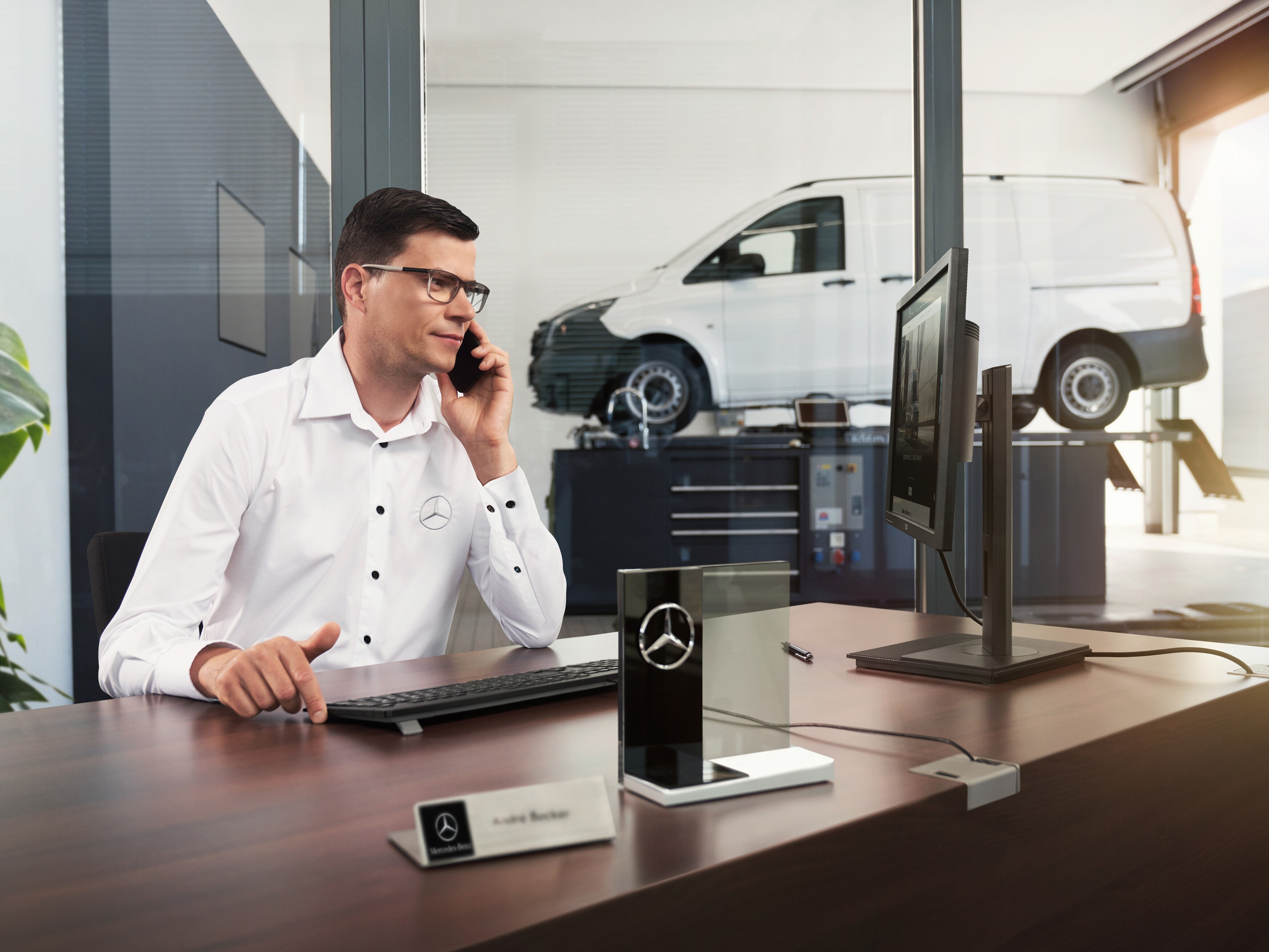 Mercedes-Benz servicerådgivare talar i telefon på en verkstad.