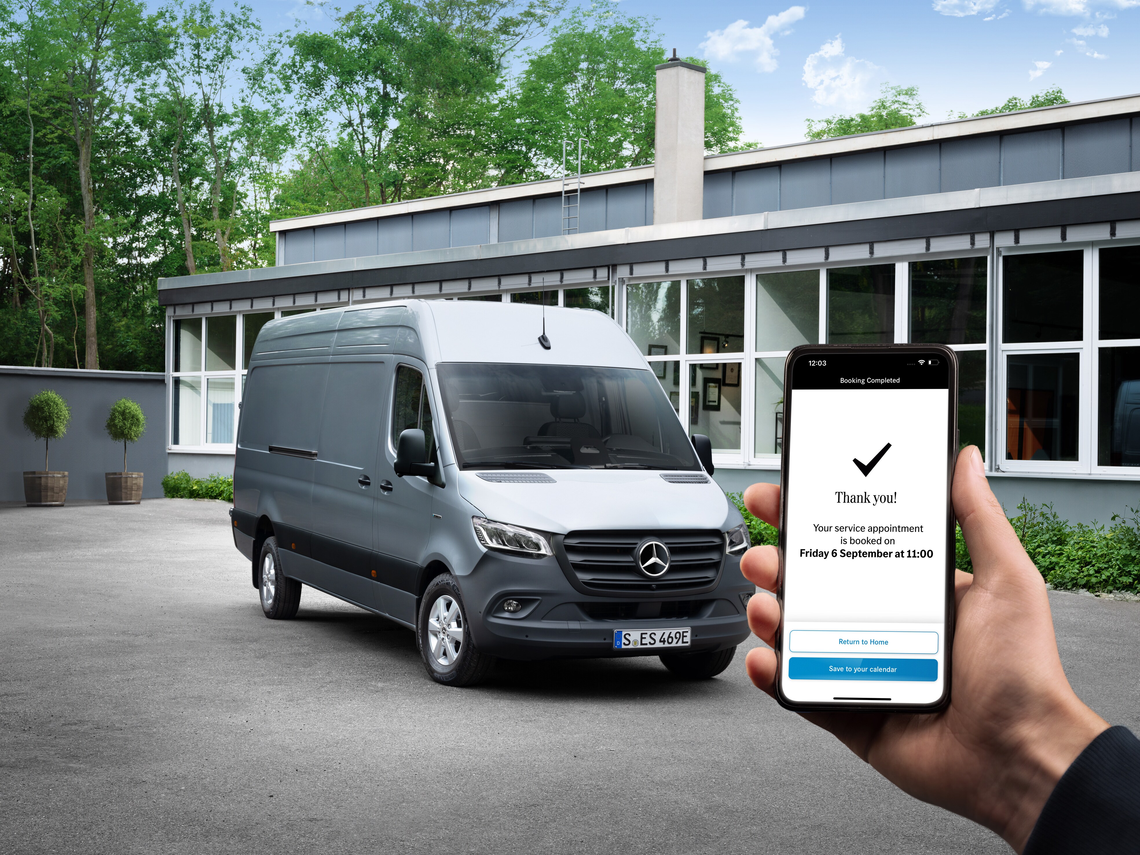 En Sprinter framför ett kontor med en person som håller i en smartphone.