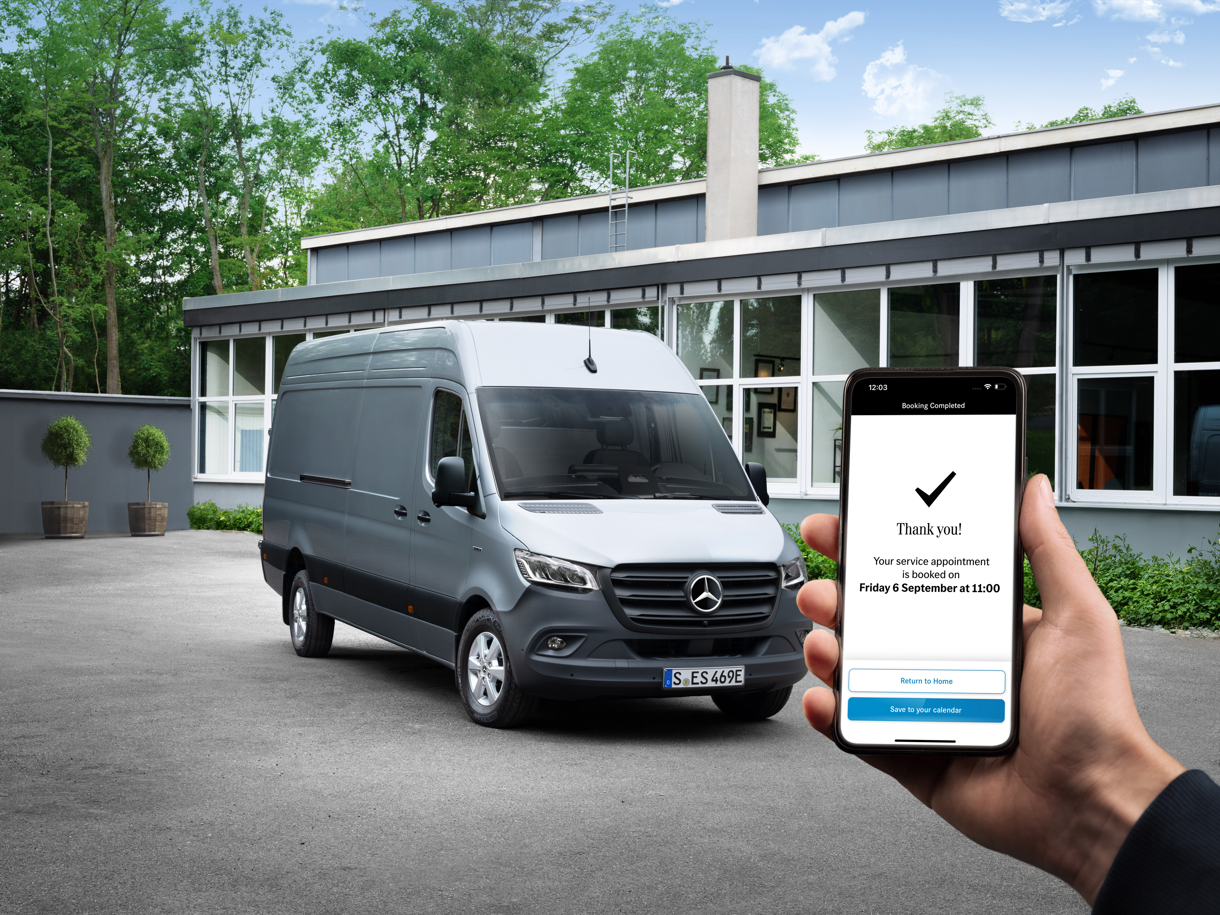 Mercedes-Benz | Bekvämlighet | Servicepartner En Sprinter framför ett kontor med en person som håller i en smartphone.