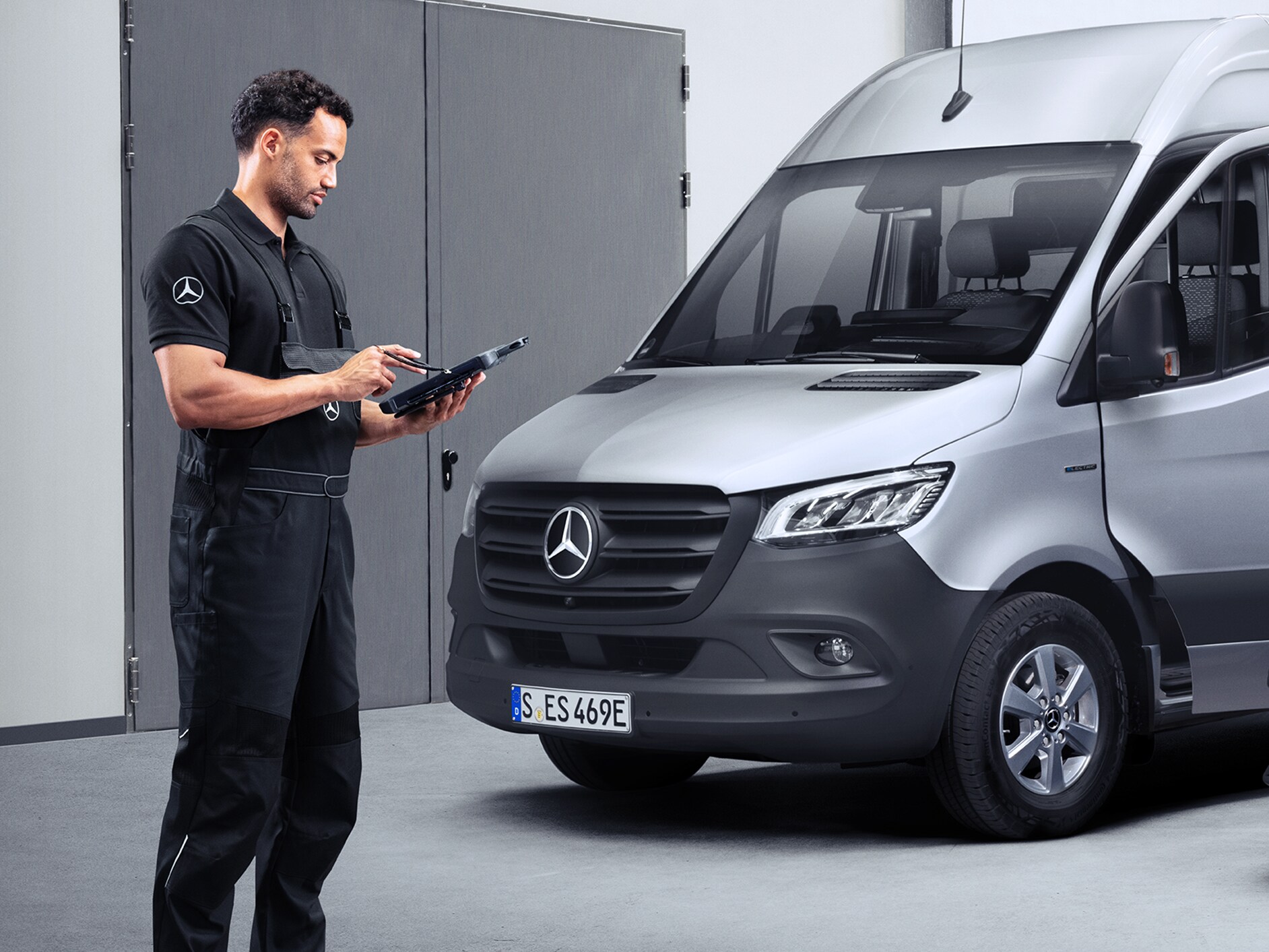 En tekniker som står framför en Mercedes-Benz Sprinter och arbetar.