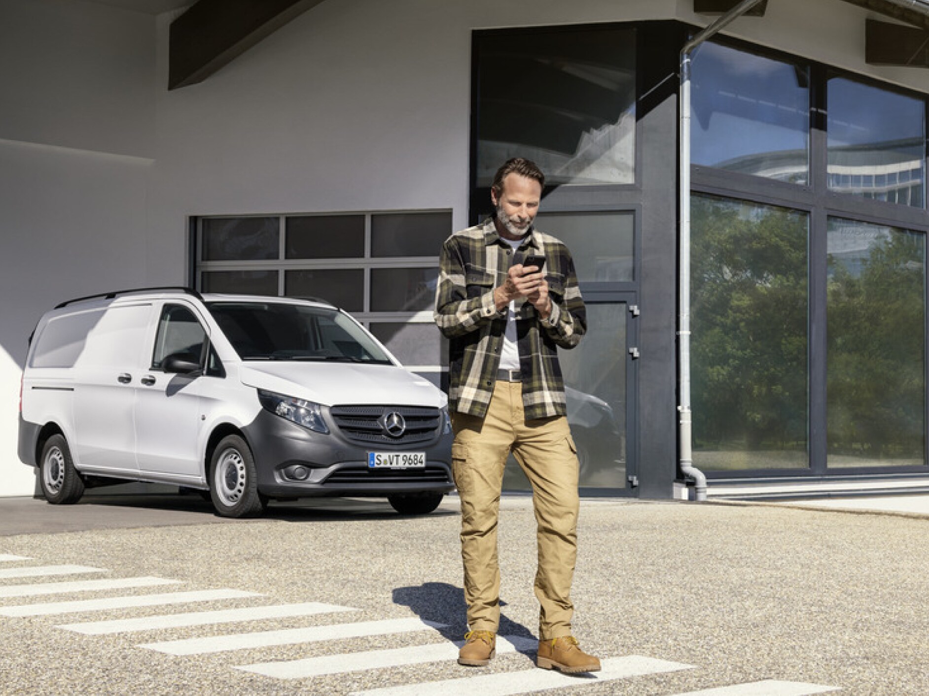 En person med en smartphone framför en Mercedes-Benz Vito.