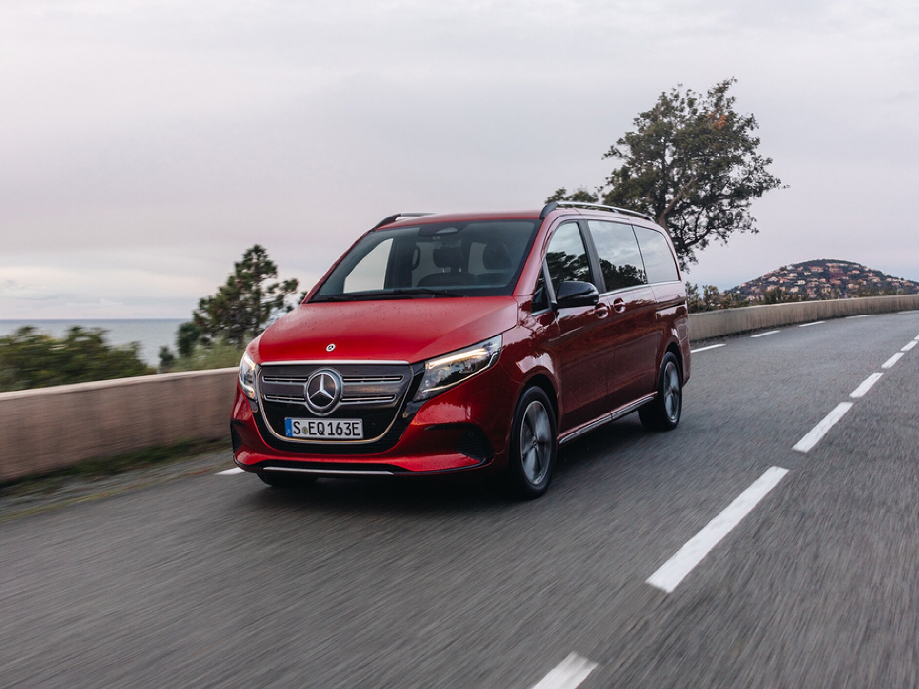 En röt Mercedes-Benz EQV på en landsväg.