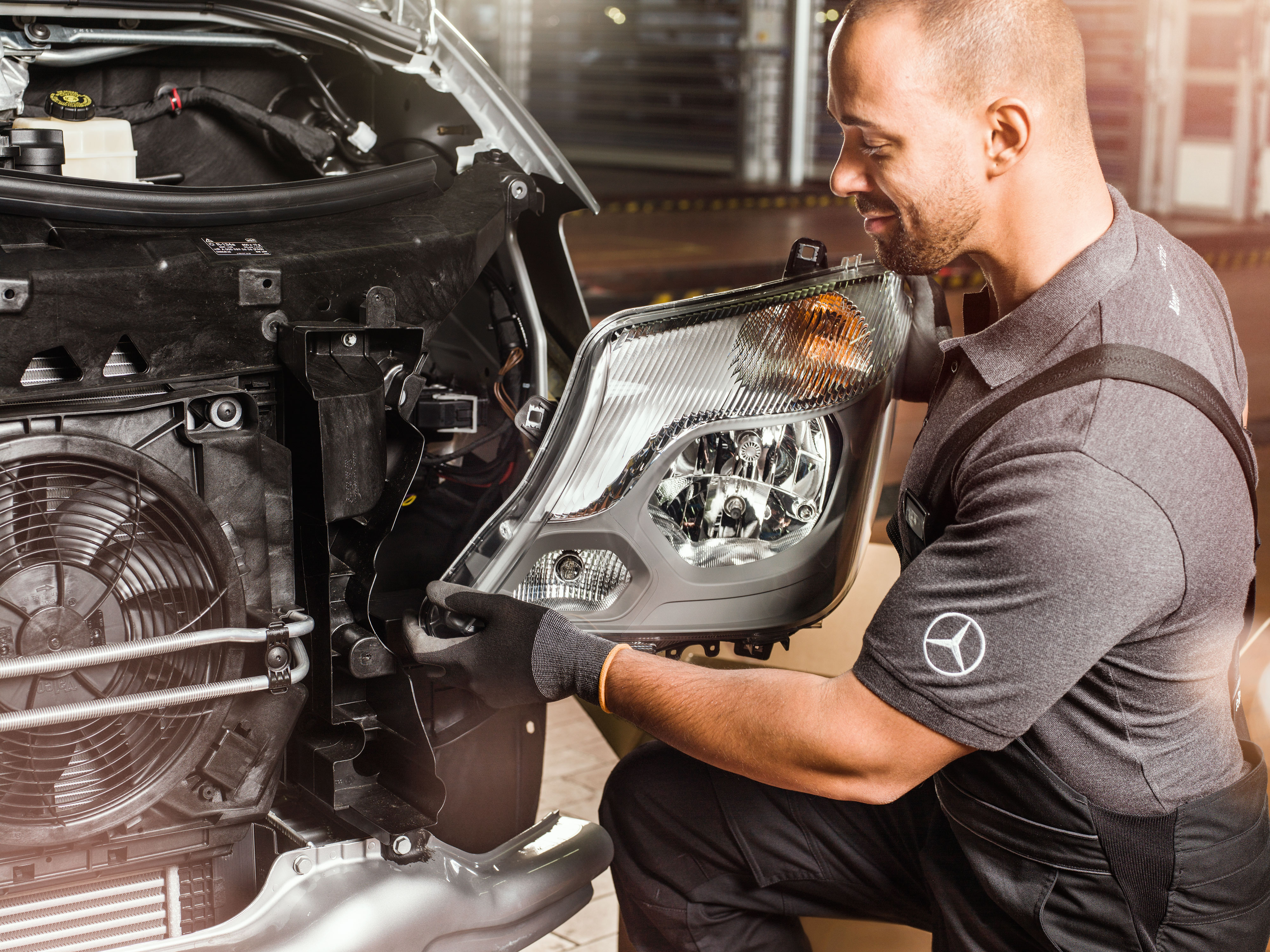 Mercedes-Benz | Transportbilar Kvalitet Originaldelar Mekaniker kontrollerar originaldelar framför en öppen Sprinter-motor.