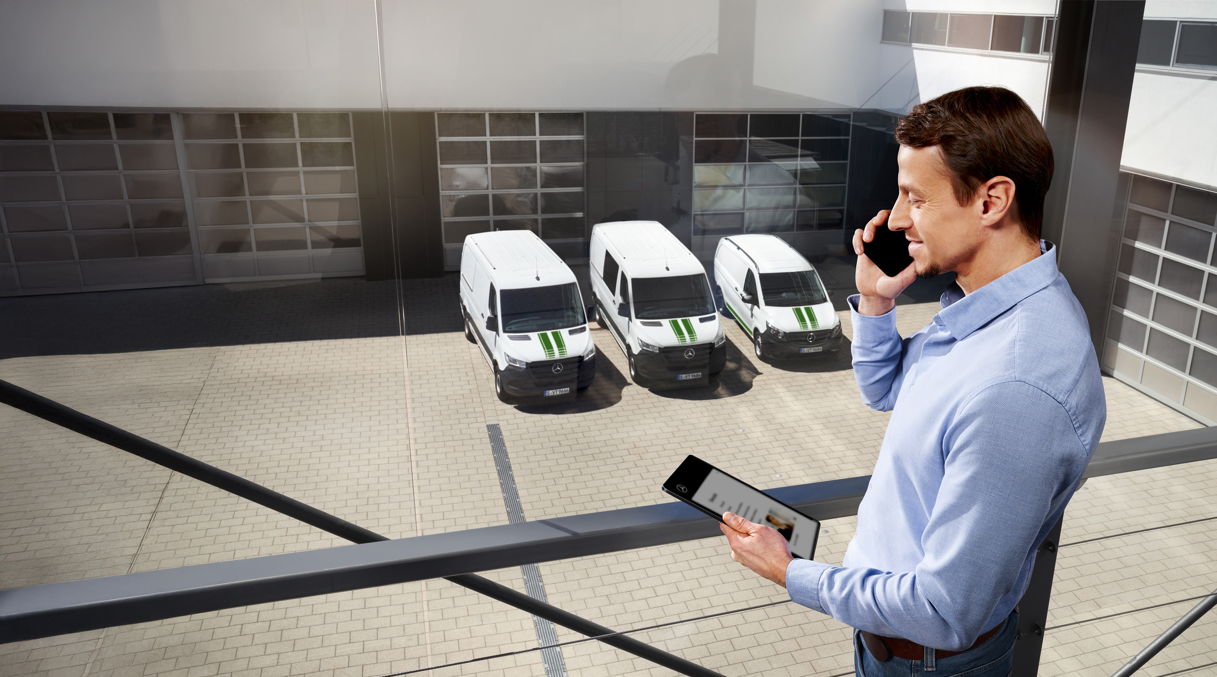 Mercedes-Benz | Transportbilar Kvalitet Garanti Man pratar i telefon med surfplatta framför tre Mercedes-Benz transportbilar.