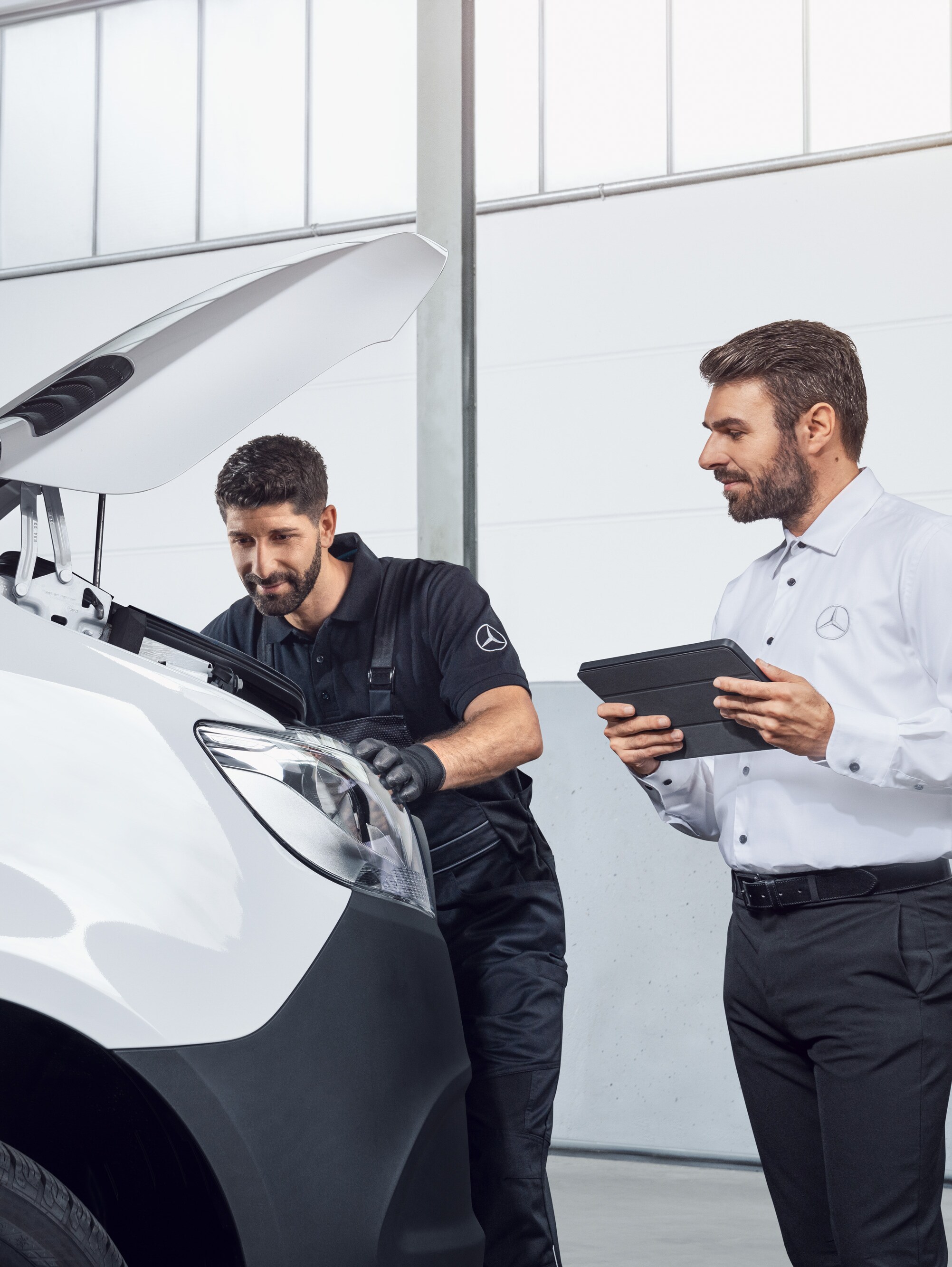 Två män testar en Mercedes Sprinter med surfplatta och öppen motorhuv, ämne: Mercedes-Benz Sprinter reservdelar.