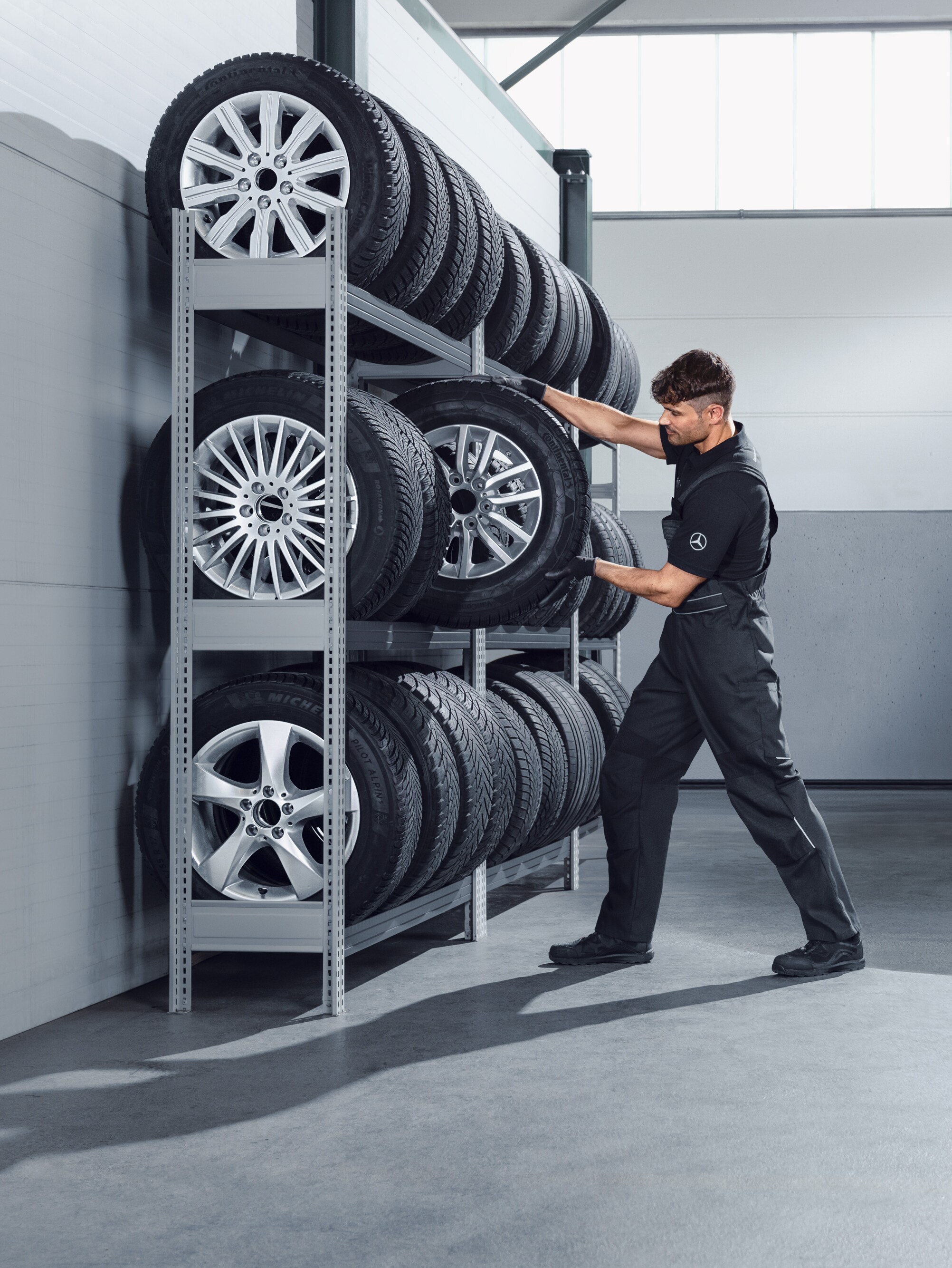 Mekaniker plockar ner Mercedes-Benz kompletta vinterhjul till en vit Sprinter från verkstadshyllan.