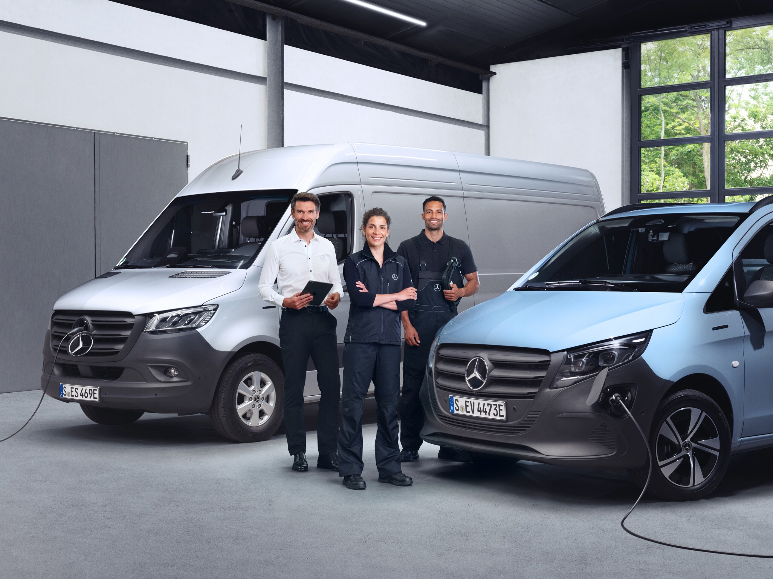 Tre medarbetare framför Mercedes-Benz transportbilar.