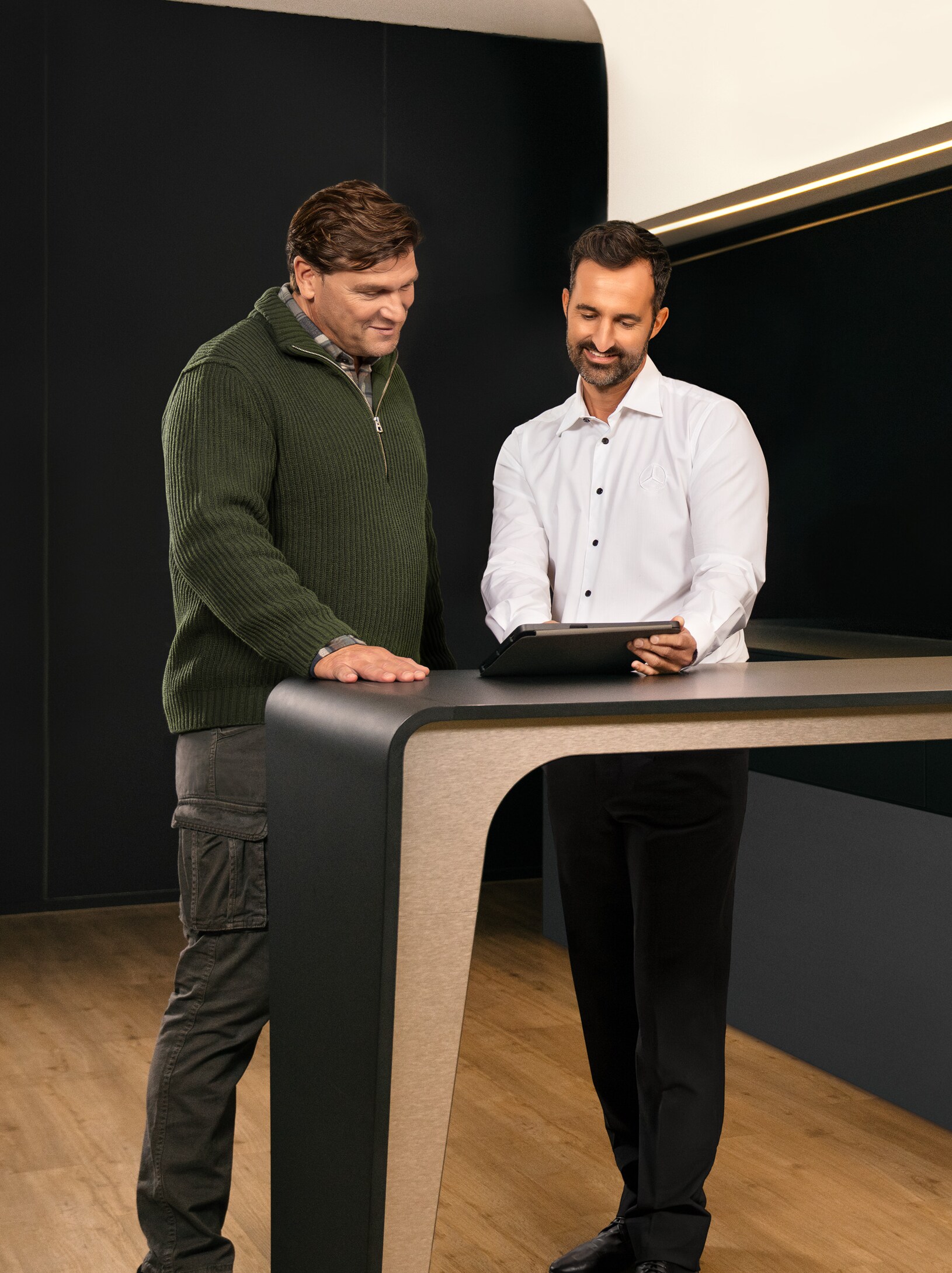 Två män har en konsultation runt ett bord och tittar på en iPad.