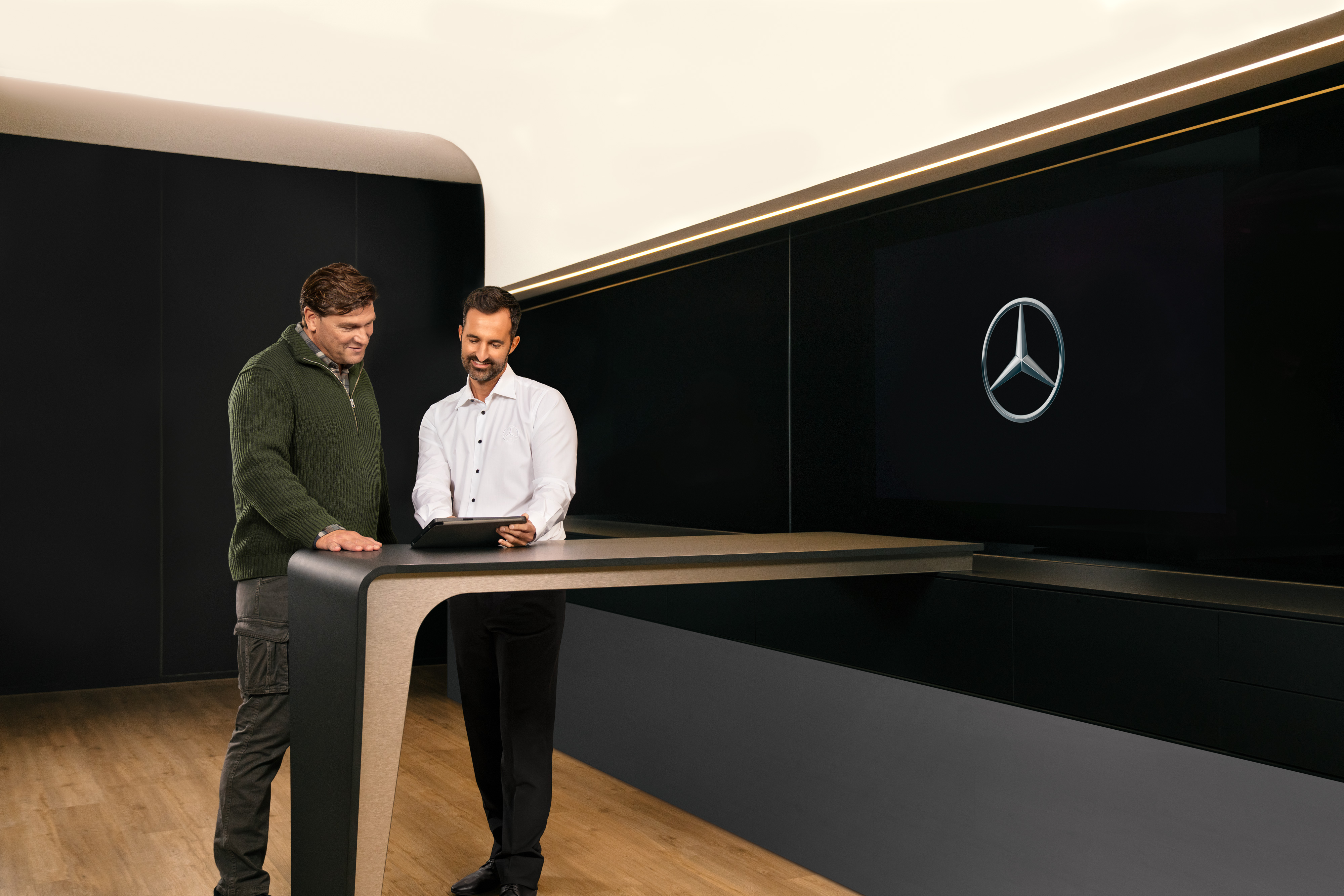 Mercedes-Benz | Van ServiceCare Två män har en konsultation runt ett bord och tittar på en iPad.