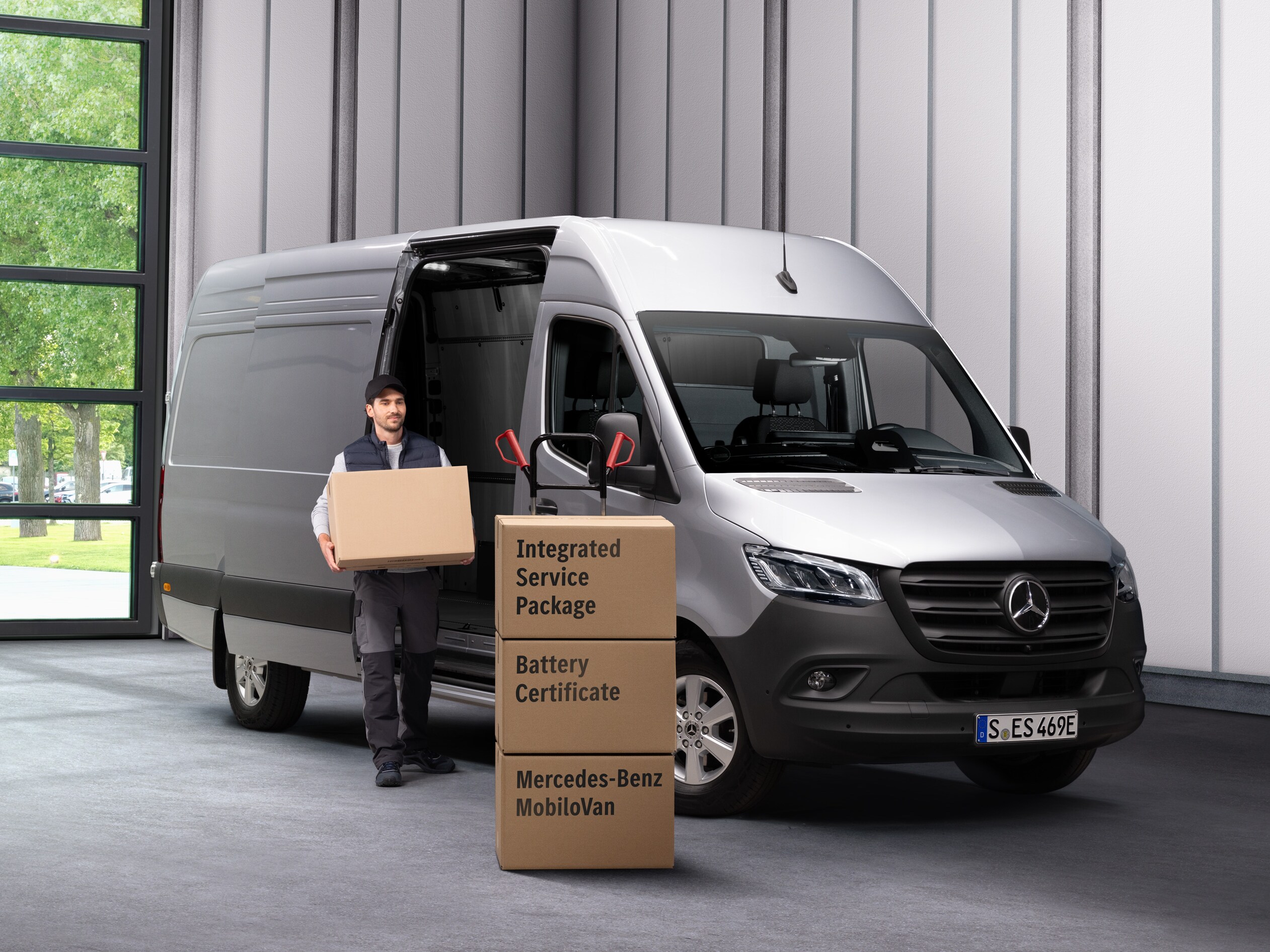 En medarbetare på Mercedes-Benz elbilsservice bär ut lådor ur en transport.
